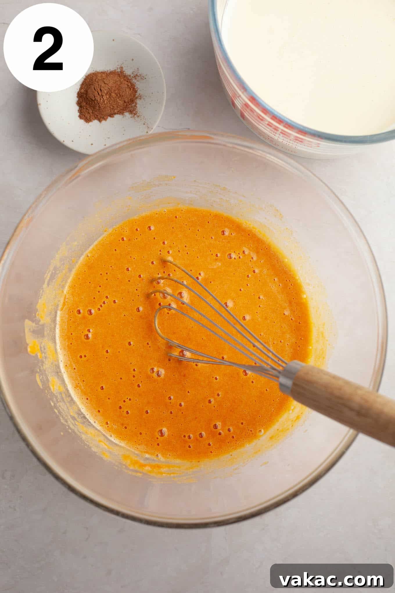 Spiced Pumpkin Creme Brulee 5 An overhead view of the pumpkin puree being gently folded into the egg yolk and sugar mixture, creating a vibrant orange custard base.
