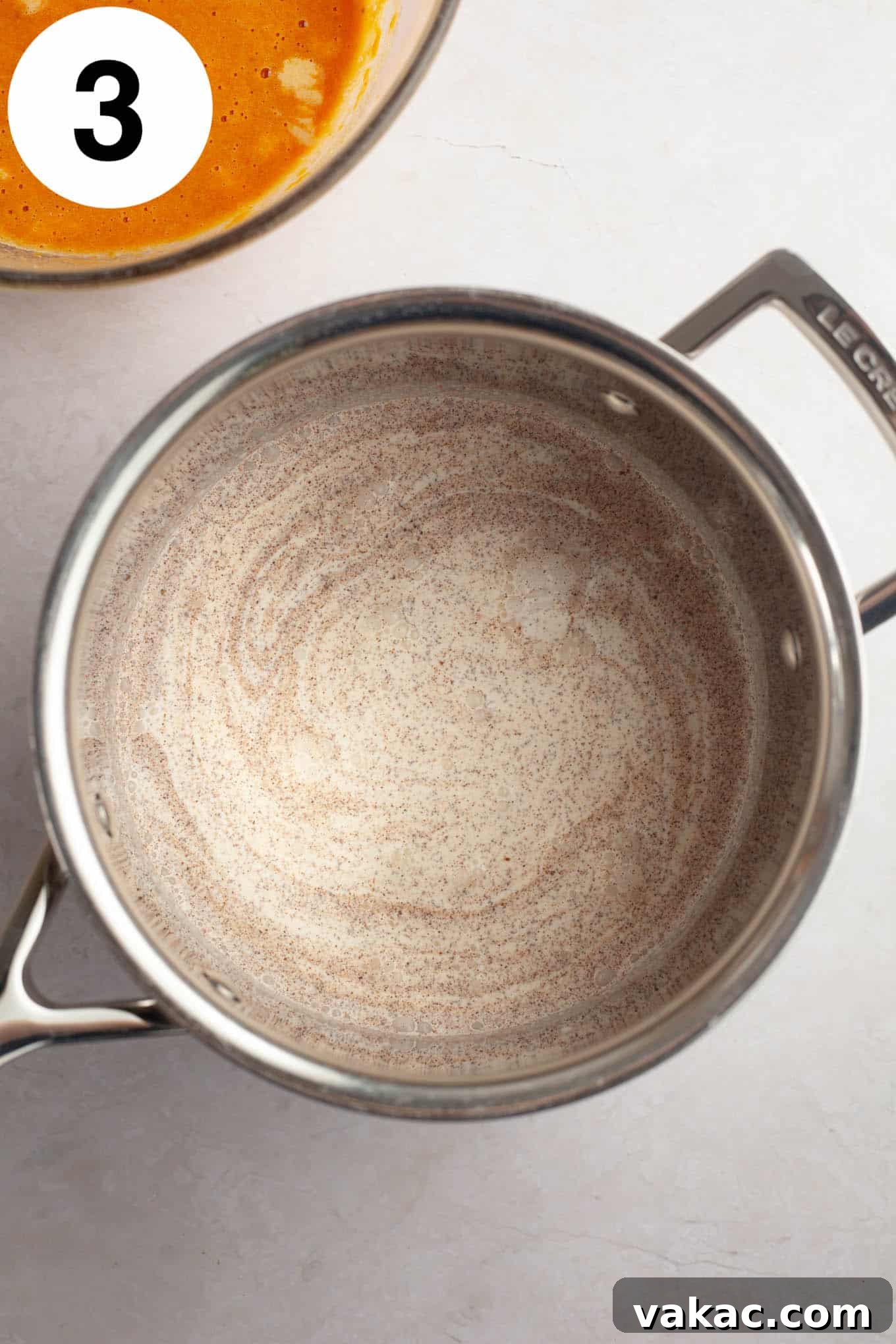 Spiced Pumpkin Creme Brulee 6 An overhead view of heavy cream and fragrant pumpkin pie spice simmering gently in a saucepan, infusing the cream with warm flavors.