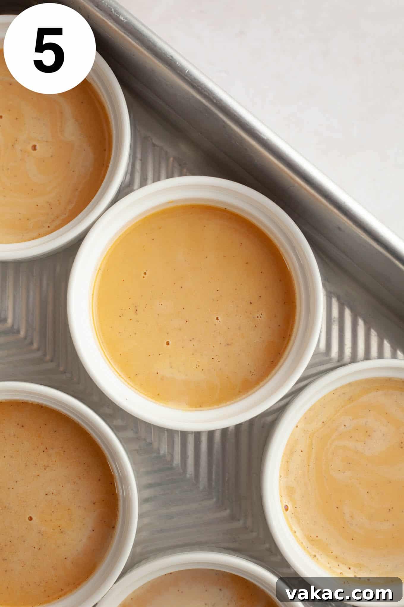 Spiced Pumpkin Creme Brulee 8 An overhead view of unbaked pumpkin crème brûlée custard elegantly poured into individual ramekins, nestled in a baking dish, ready for the water bath.