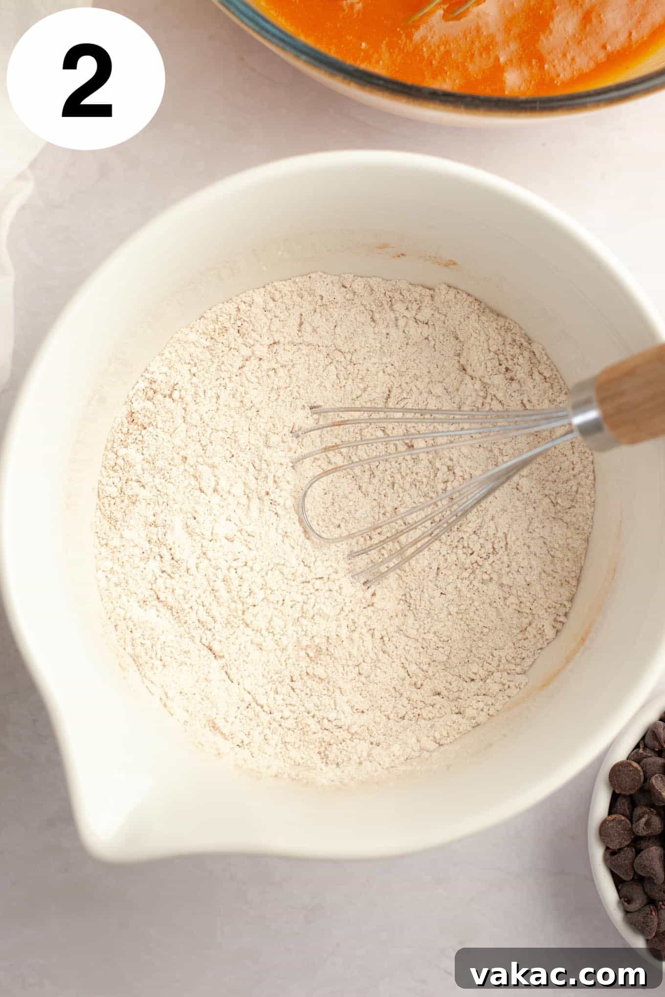 Harvest Pumpkin Chocolate Chip Muffins 5 An overhead view of a dry flour mixture in a mixing bowl, with a whisk.
