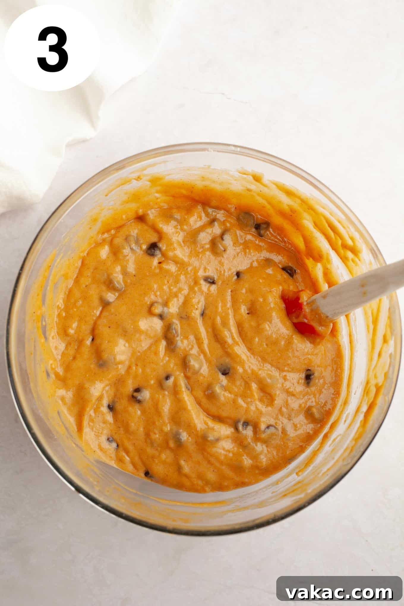 Harvest Pumpkin Chocolate Chip Muffins 6 An overhead view of pumpkin chocolate chip muffin batter in a mixing bowl, with a rubber spatula.