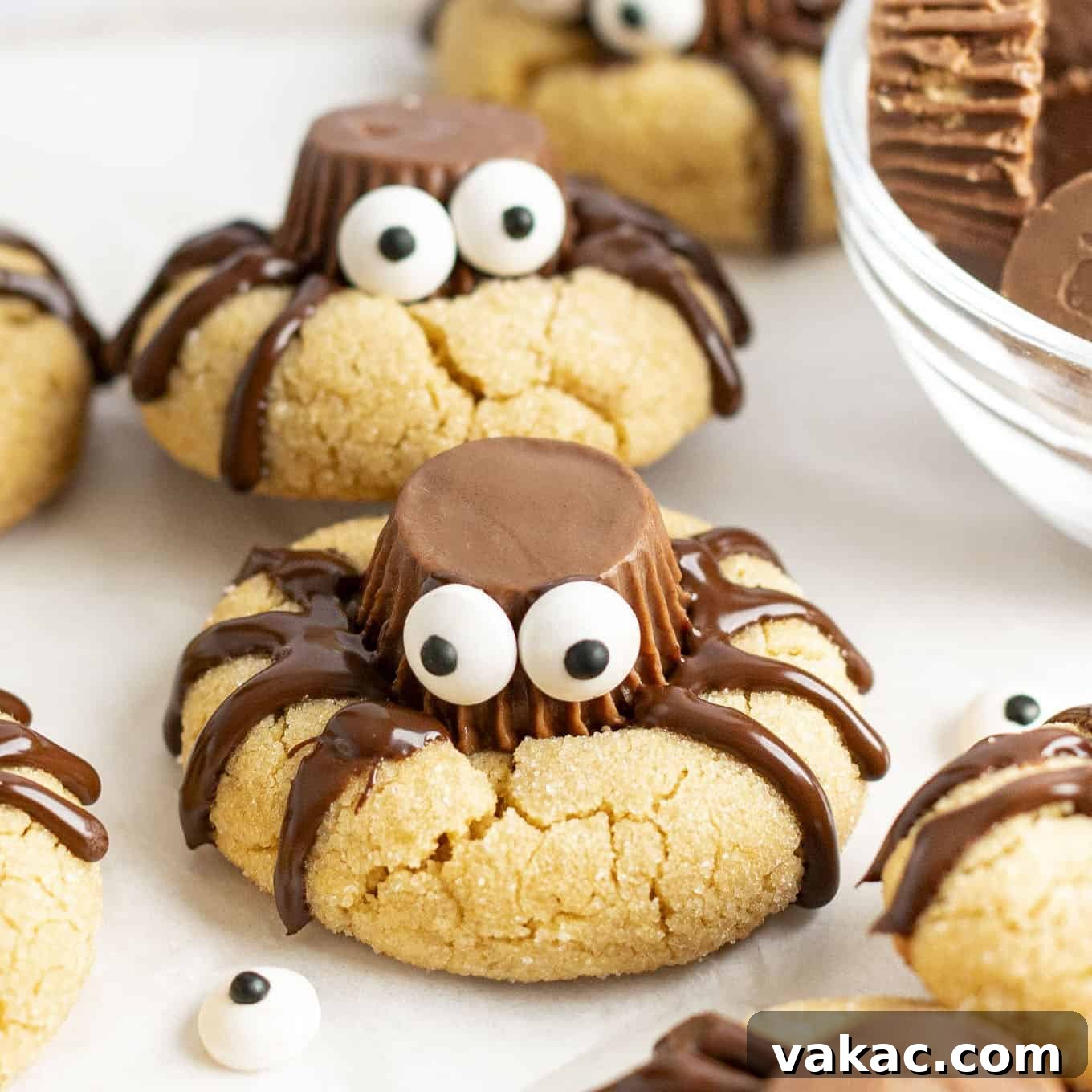 A closeup of spider cookies on a piece of parchment paper.
