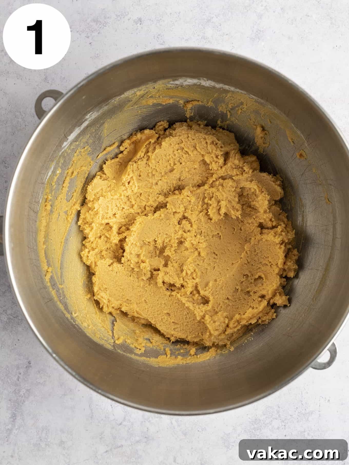 An overhead view of peanut butter cookie dough in a metal mixing bowl.