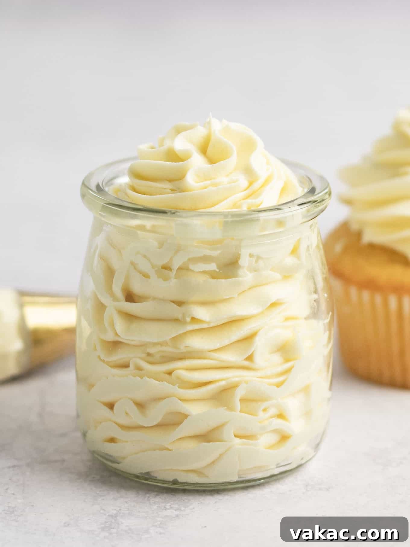 Velvet White Chocolate Frosting 6 A clear glass container filled to the brim with beautifully piped white chocolate buttercream, showcasing its smooth texture.