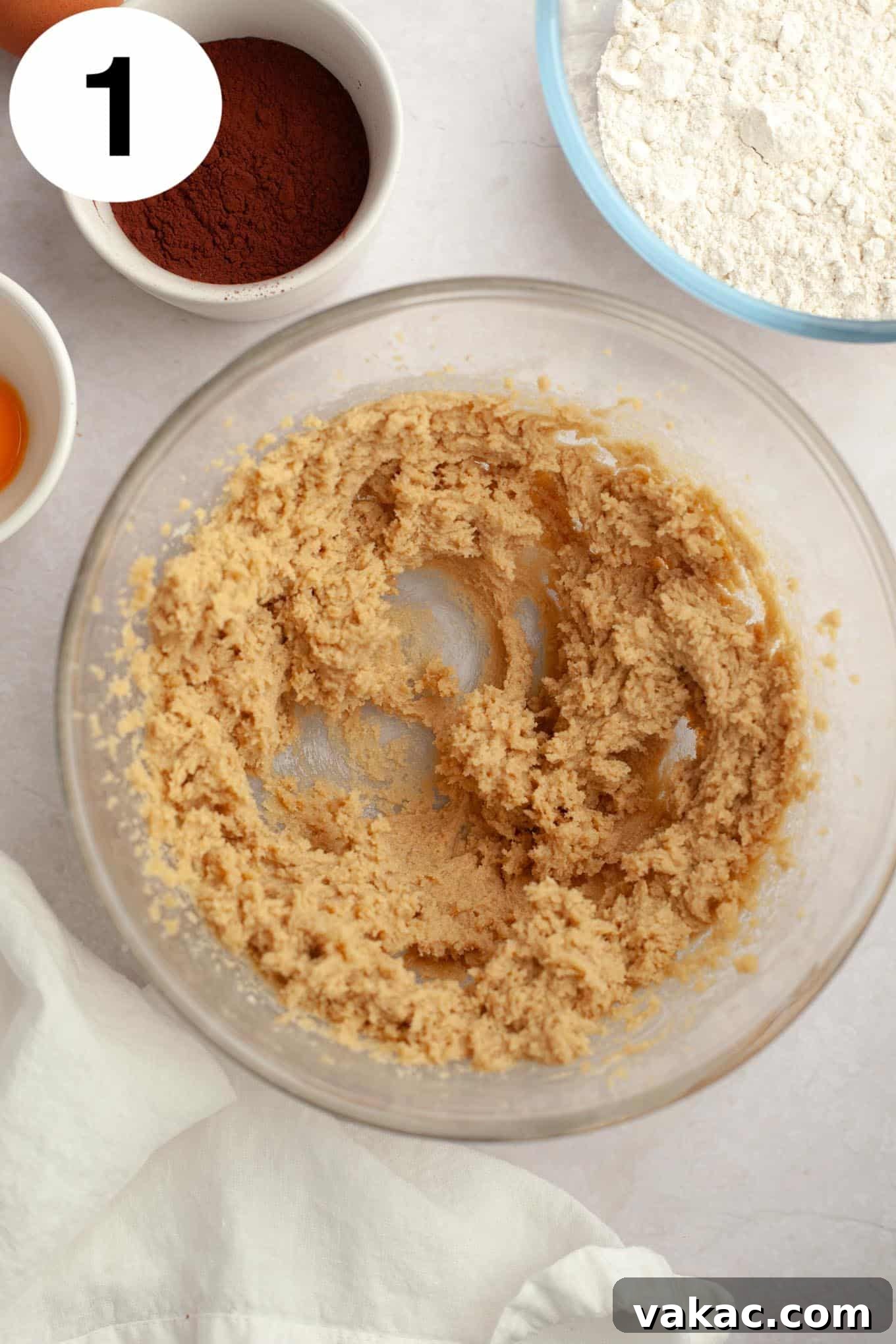An overhead view of creamed butter and brown sugar in a glass mixing bowl.