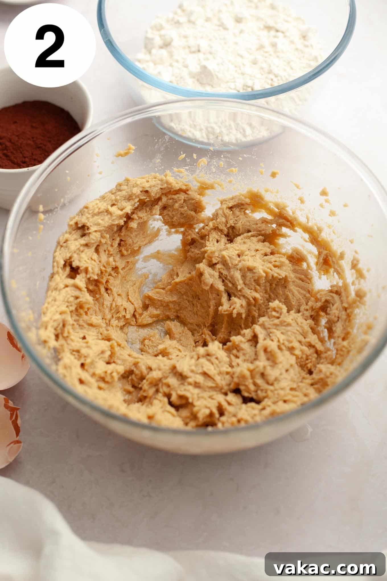 An overhead view of the wet ingredients for Buckeye cookies in a glass mixing bowl.