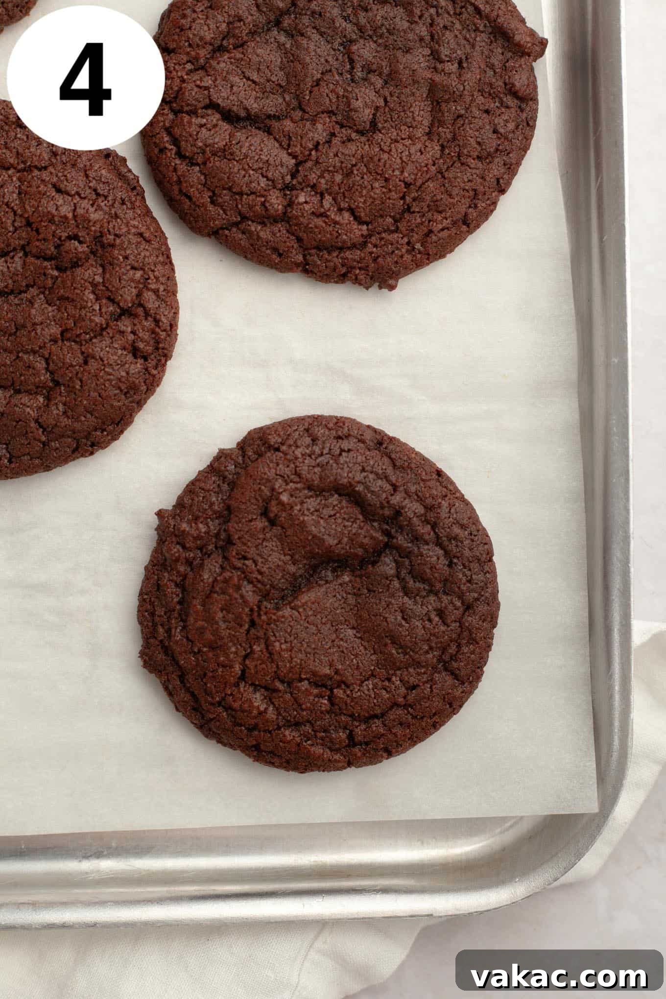 An overhead view of chocolate cookies on a parchment-lined baking sheet.