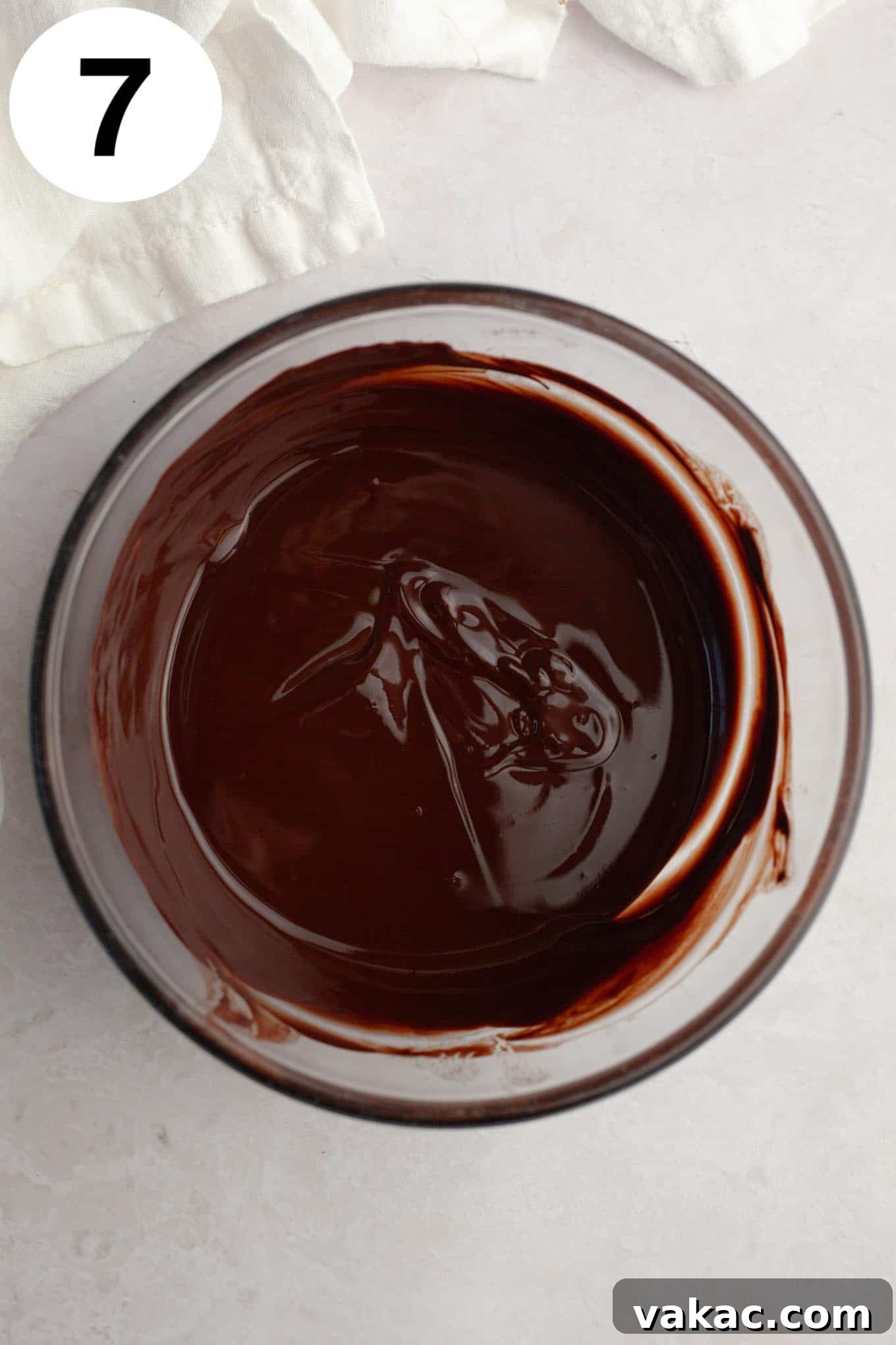 An overhead view of melted chocolate in a glass bowl.
