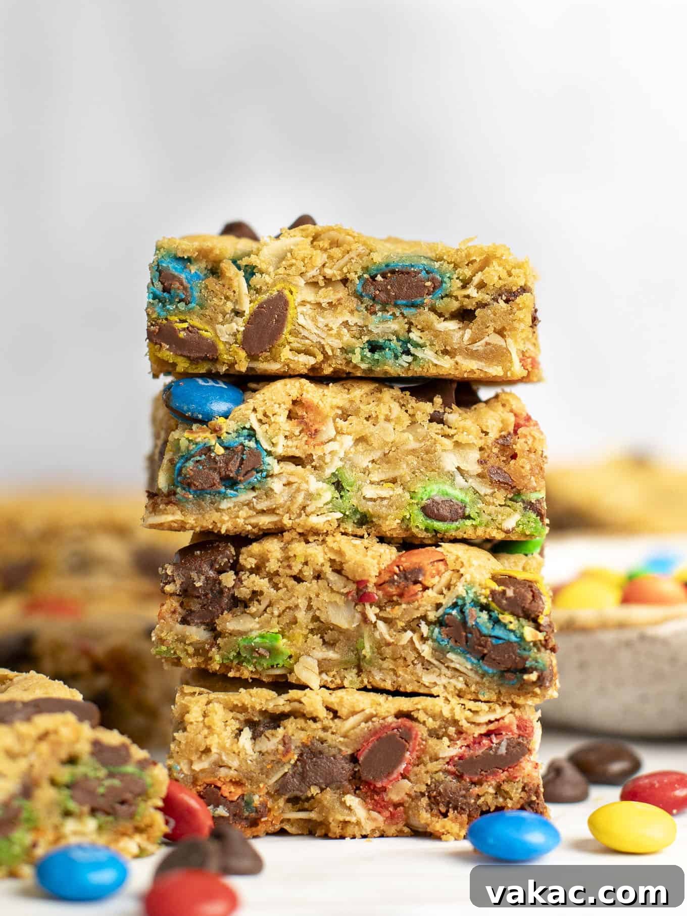 Ultimate Everything Cookie Bars 2 A stack of four perfectly baked monster cookie bars, beautifully arranged and surrounded by colorful M&M's, inviting you to take a bite.