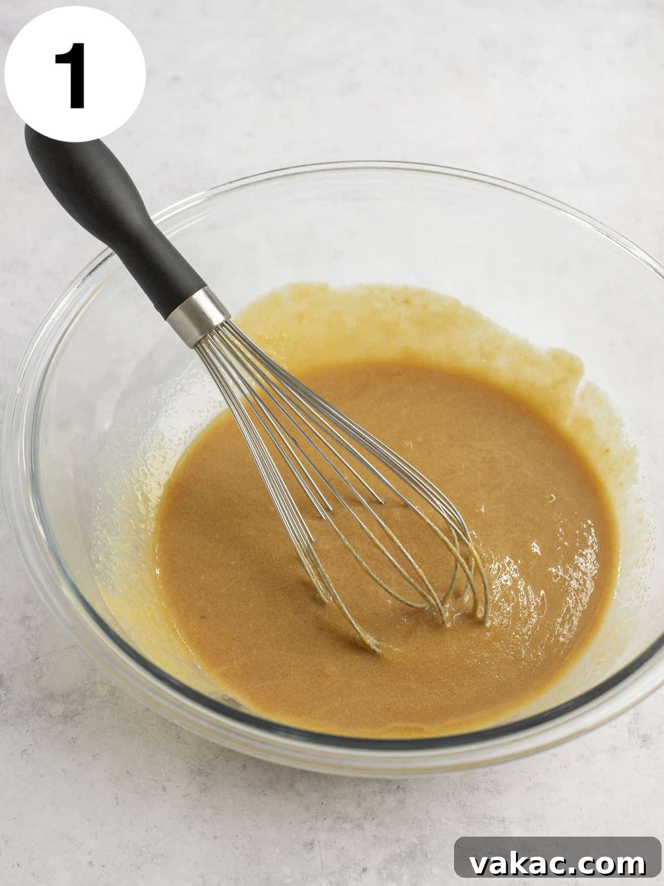 Ultimate Everything Cookie Bars 4 Melted butter and creamy peanut butter being whisked together in a clear glass mixing bowl, creating a smooth base for the cookie dough.