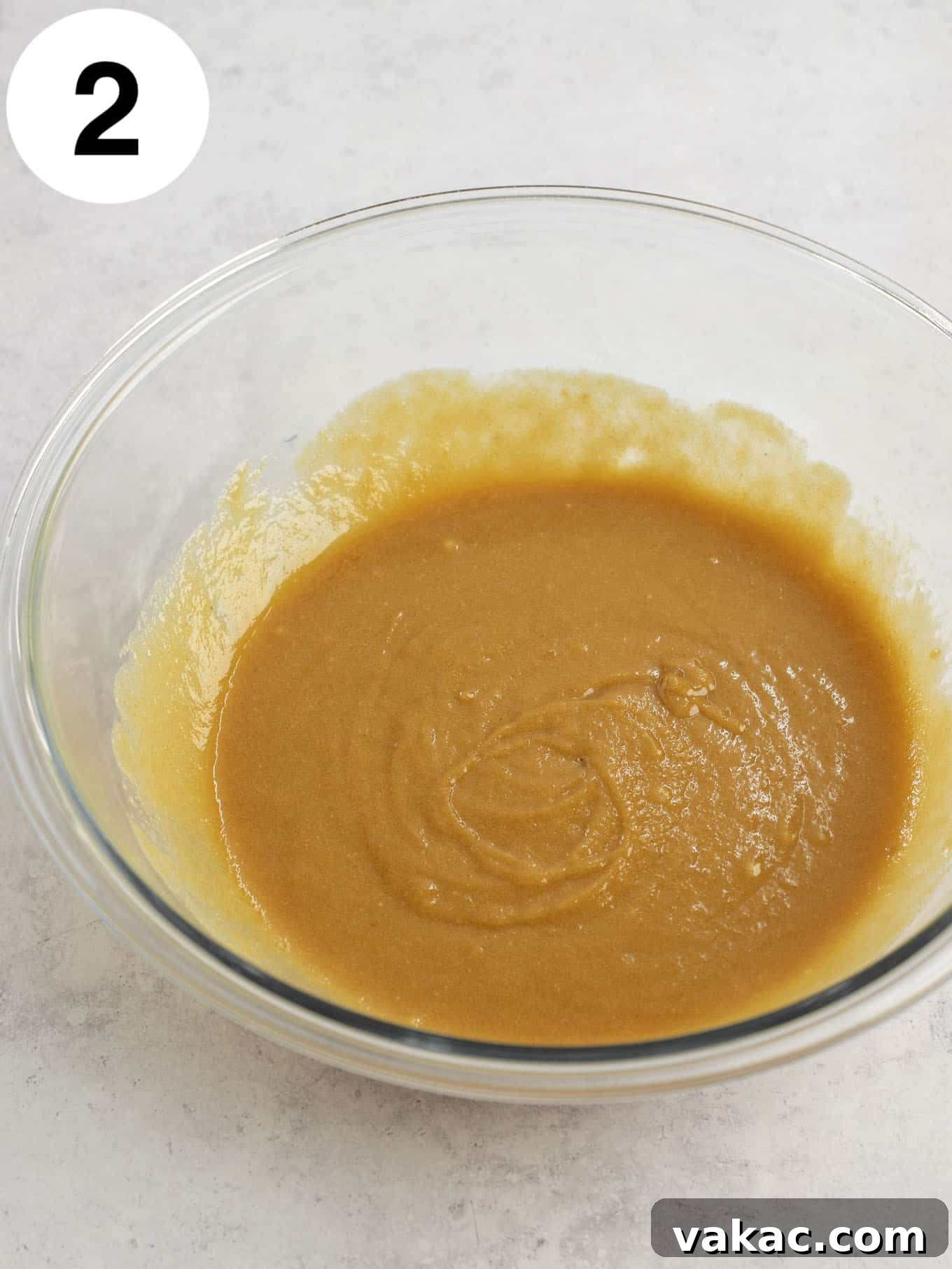 Ultimate Everything Cookie Bars 5 Melted butter, peanut butter, eggs, and brown sugar combined in a glass mixing bowl, being whisked to a smooth and creamy consistency.