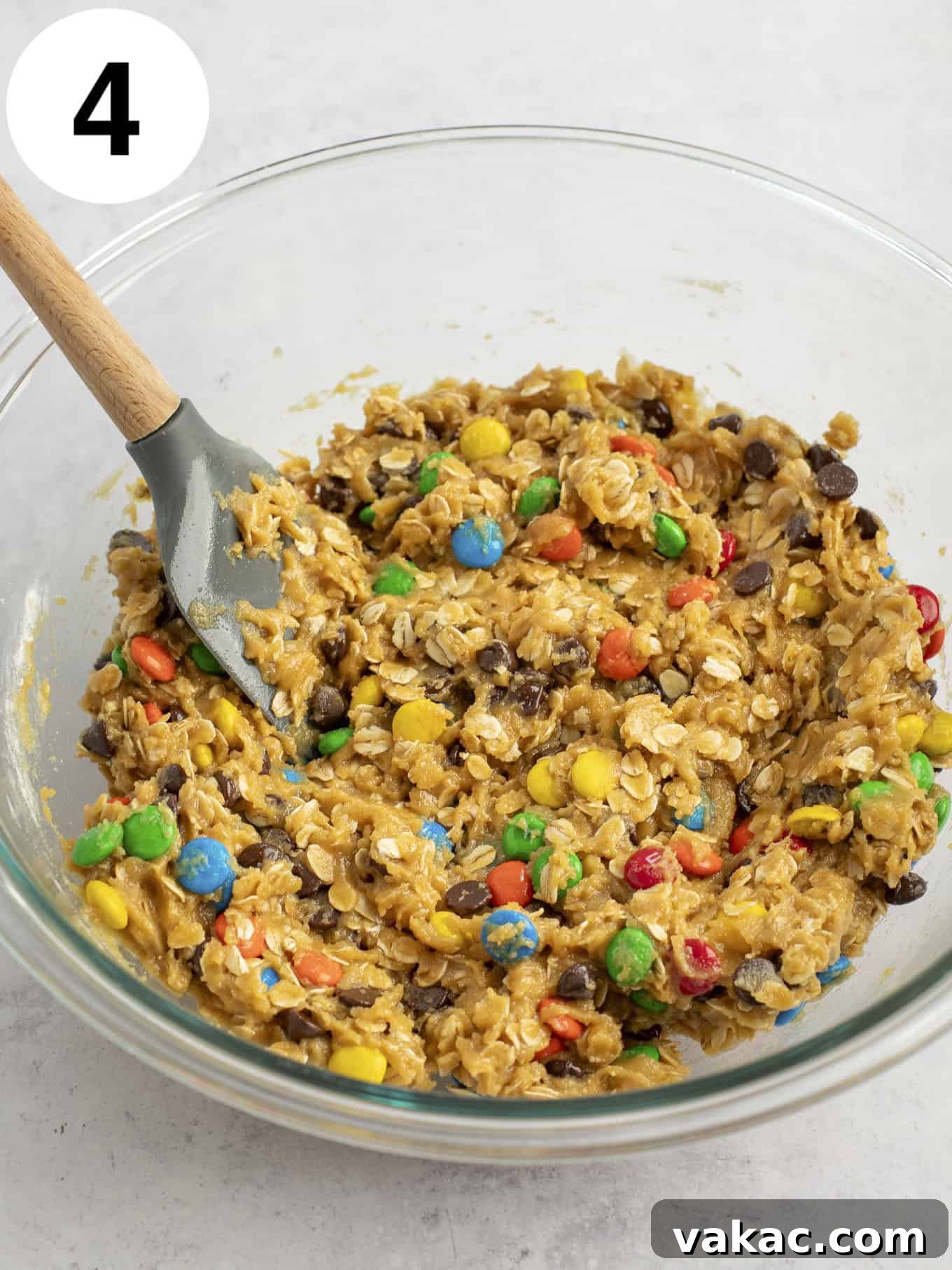 Ultimate Everything Cookie Bars 7 Completed monster cookie dough in a glass mixing bowl, filled with M&M's and chocolate chips, ready to be pressed into a pan.
