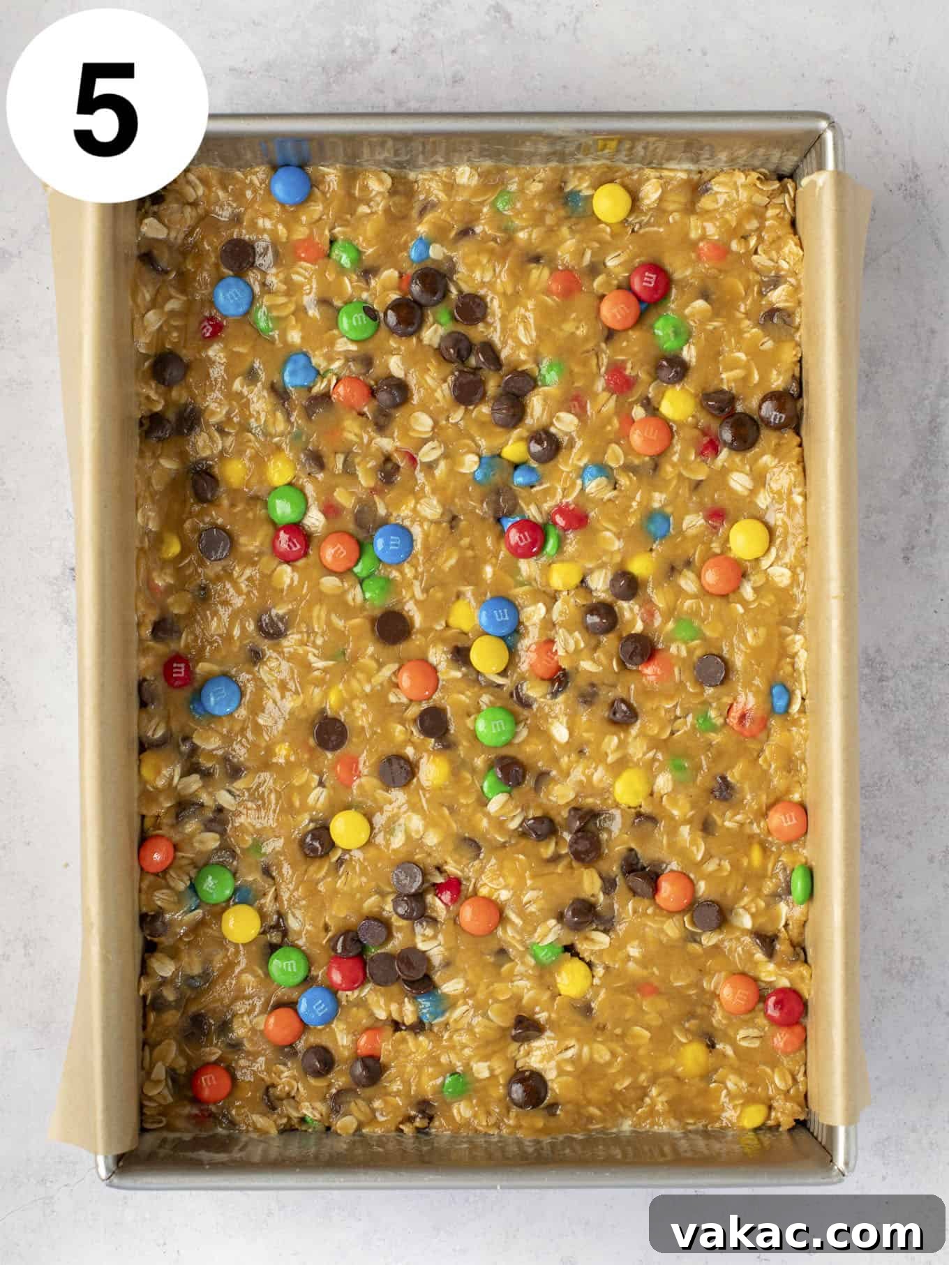 Ultimate Everything Cookie Bars 8 An overhead view of the unbaked monster cookie dough, pressed evenly into a parchment-lined 9x13-inch baking dish, ready for the oven.