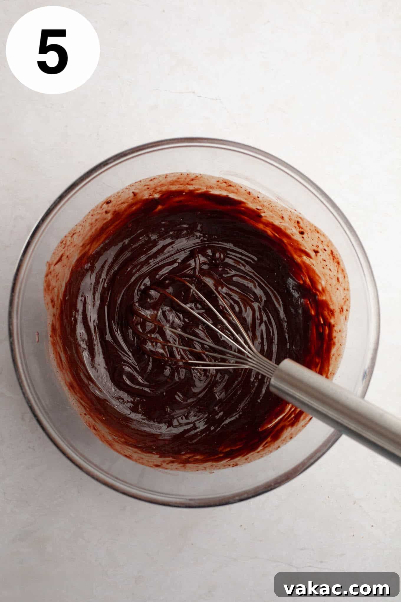 Decadent Chocolate Thumbprint Delights 8 An overhead view of luscious melted chocolate ganache in a glass mixing bowl, with a whisk ready to create a smooth filling.