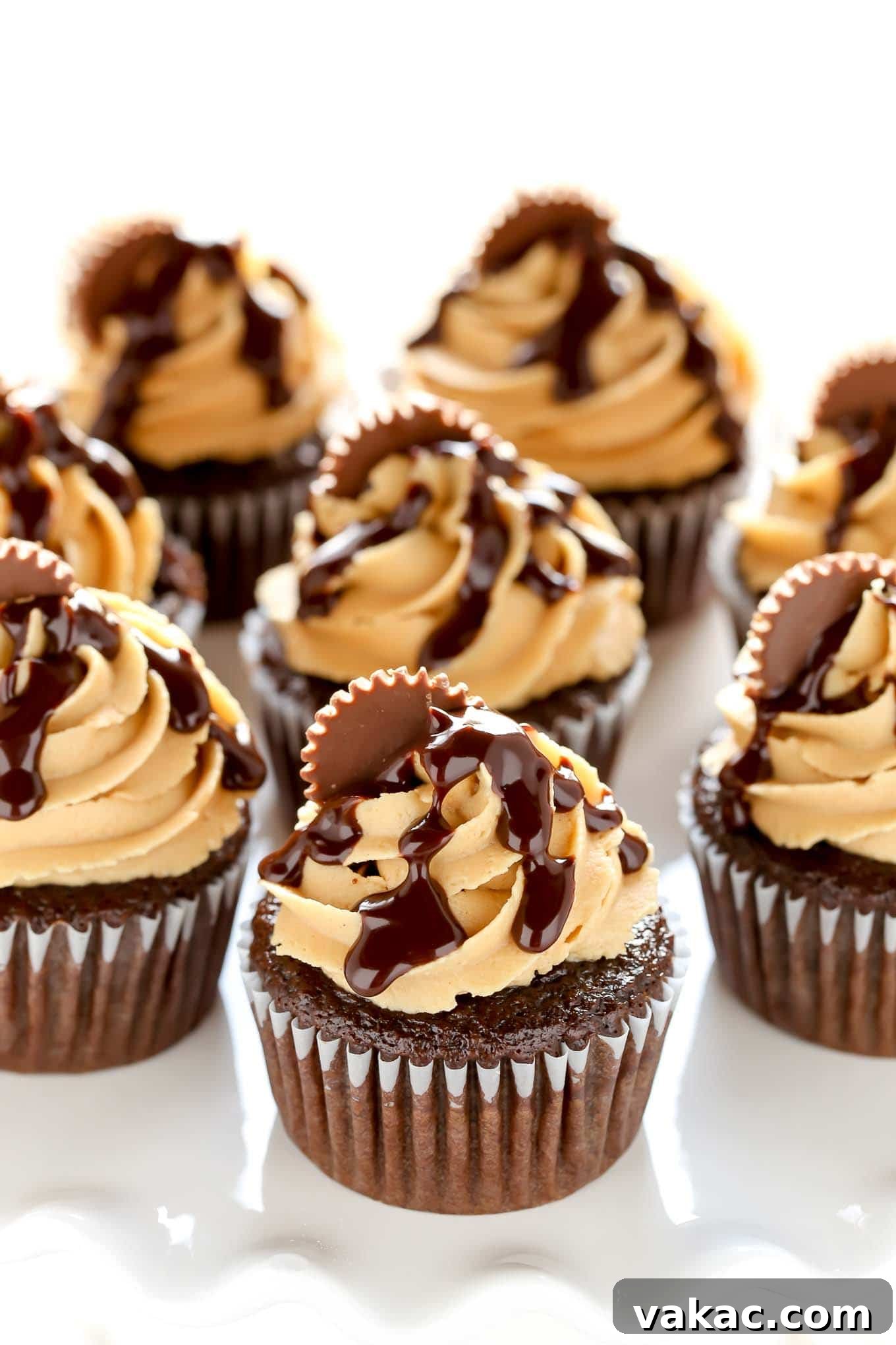 Peanut Butter Cup Chocolate Cupcakes 3 Chocolate cupcakes beautifully decorated with creamy peanut butter frosting, arranged on a pristine white cake stand.
