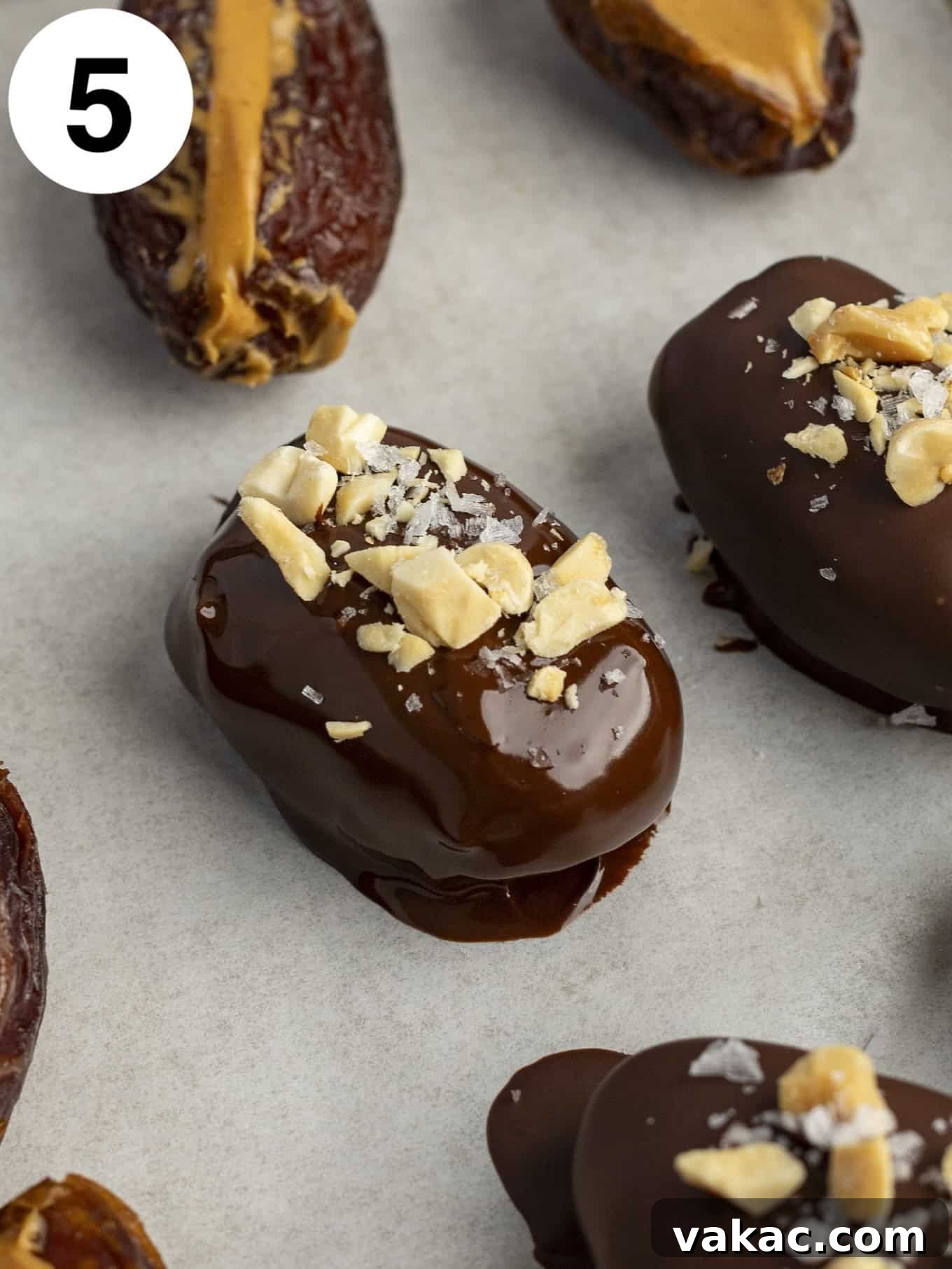 Date Peanut Chocolate Bites 8 A process shot showing a chocolate coated date topped with peanuts and sea salt.