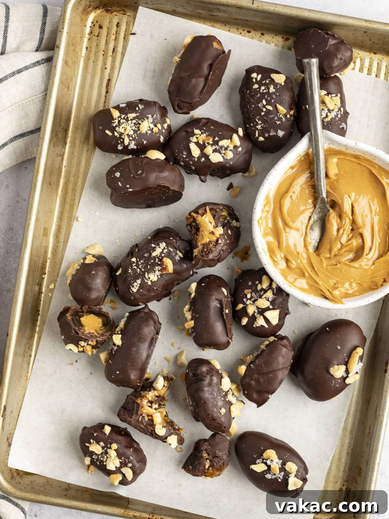 Date Peanut Chocolate Bites 10 An overhead view of date Snickers arranged on a baking sheet, with a bowl of peanut butter.