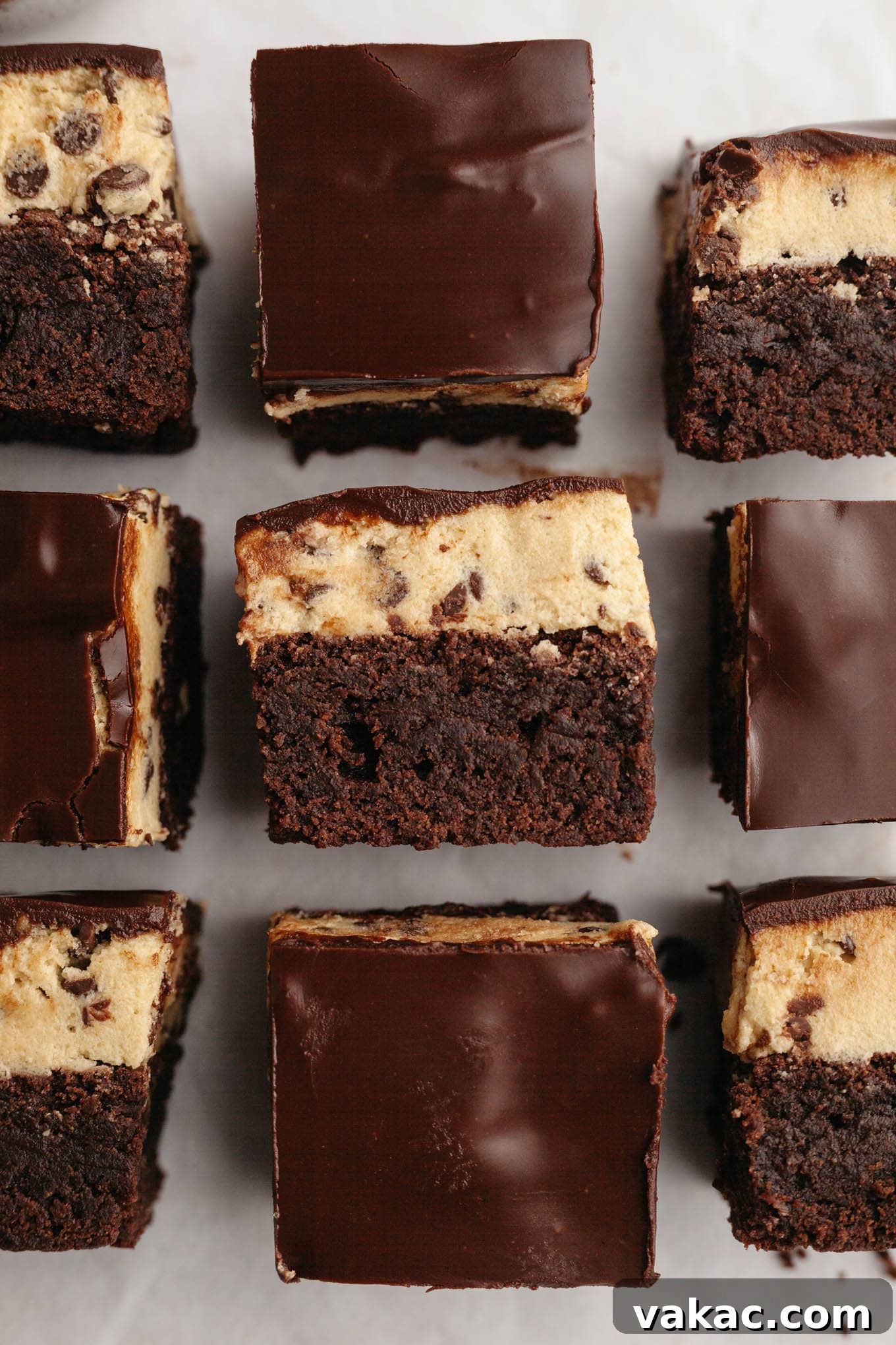 Brownie Cookie Dough Perfection 2 An overhead view of sliced cookie dough brownies, some of which are turned on their sides, showcasing the distinct layers of brownie, cookie dough, and chocolate topping.