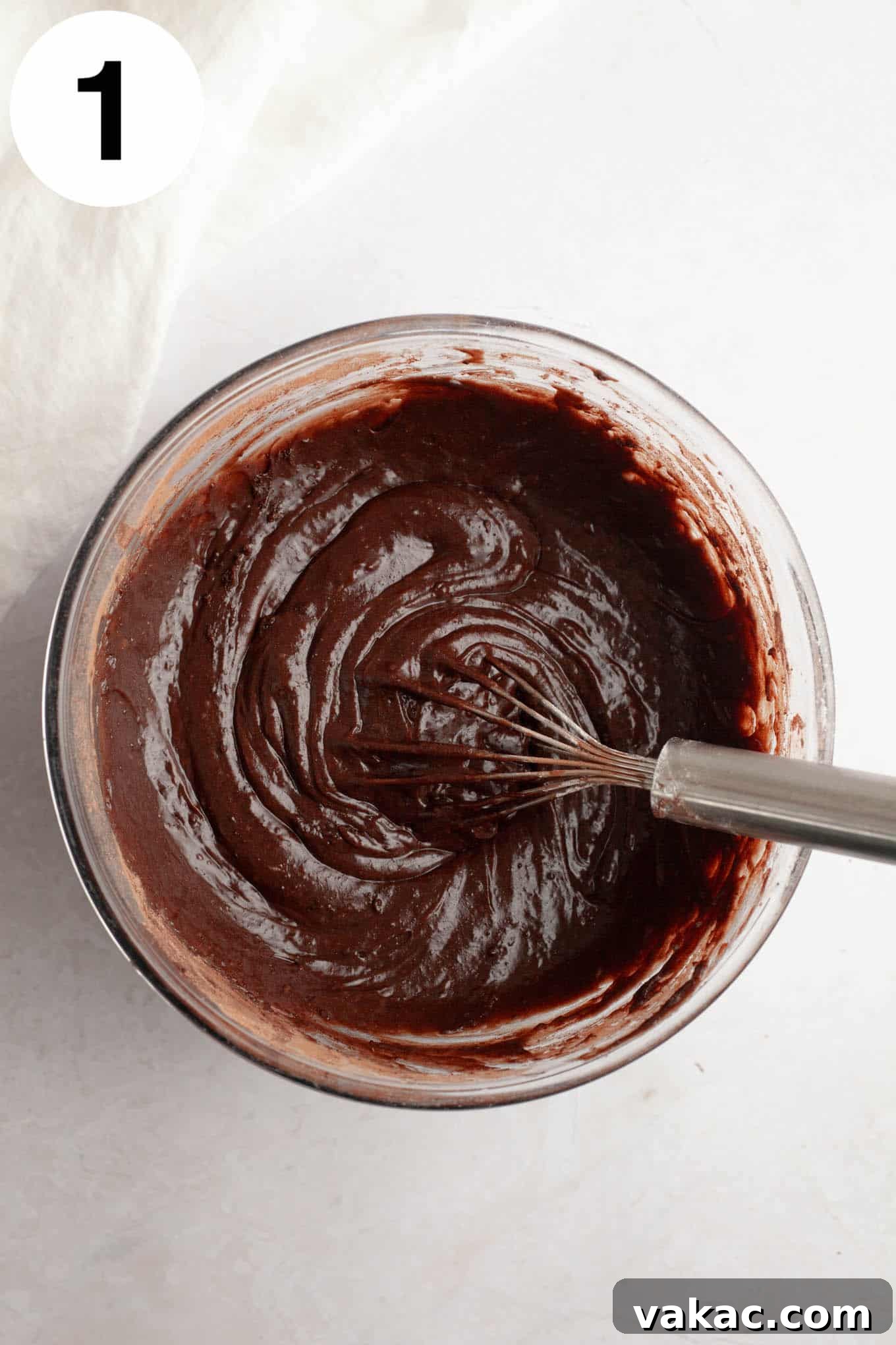 Brownie Cookie Dough Perfection 4 An overhead view of rich, dark brownie batter being whisked smooth in a clear glass mixing bowl, ready for baking.