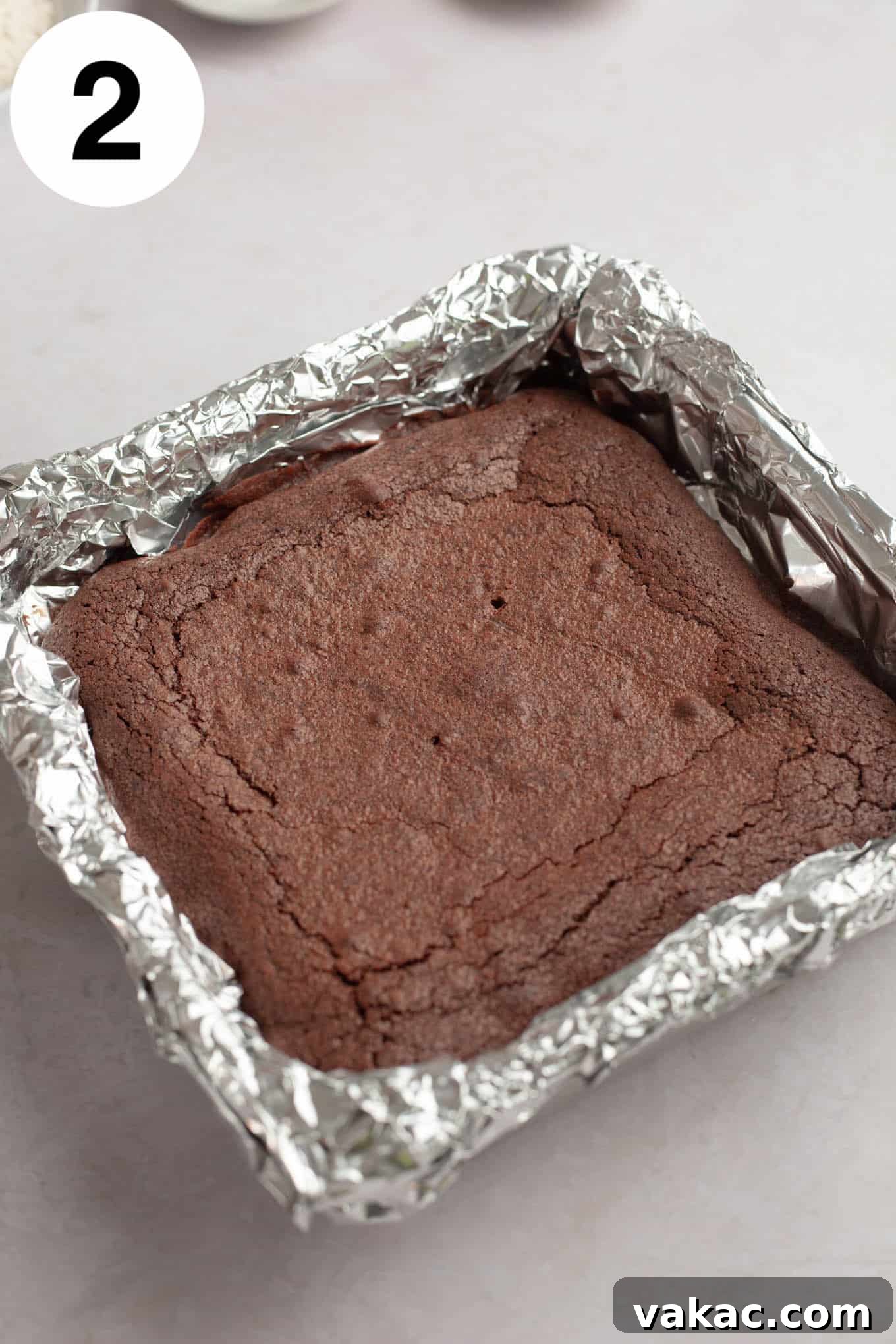 Brownie Cookie Dough Perfection 5 Freshly baked, glossy chocolate brownies resting in a foil-lined square pan, their edges slightly crisp and center soft.