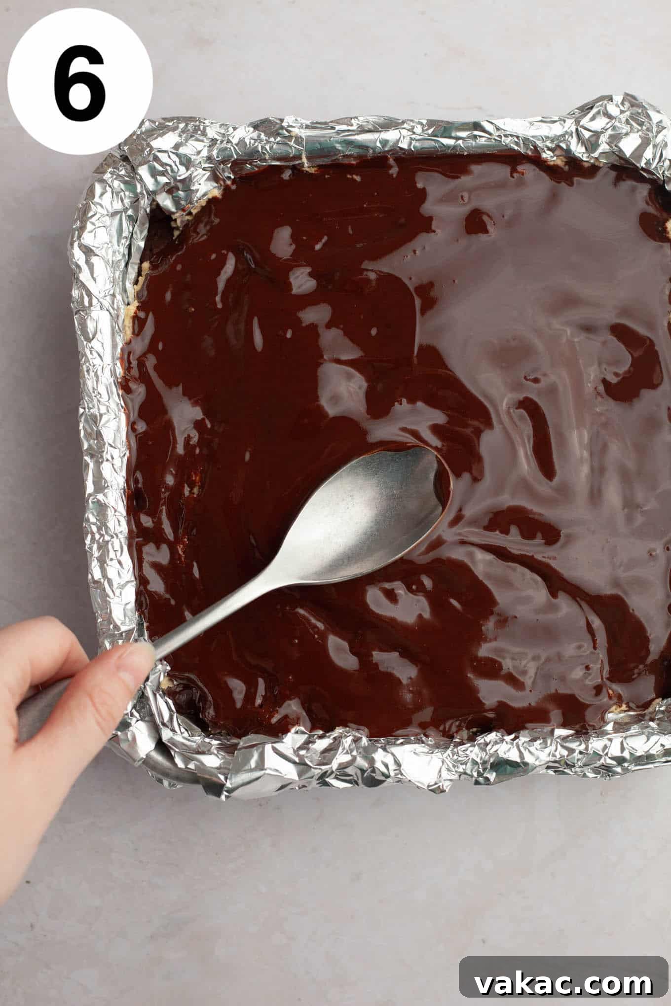 Brownie Cookie Dough Perfection 9 An overhead view of smooth, melted chocolate being evenly spread over the cookie dough layer of the brownies, creating a final glossy finish.