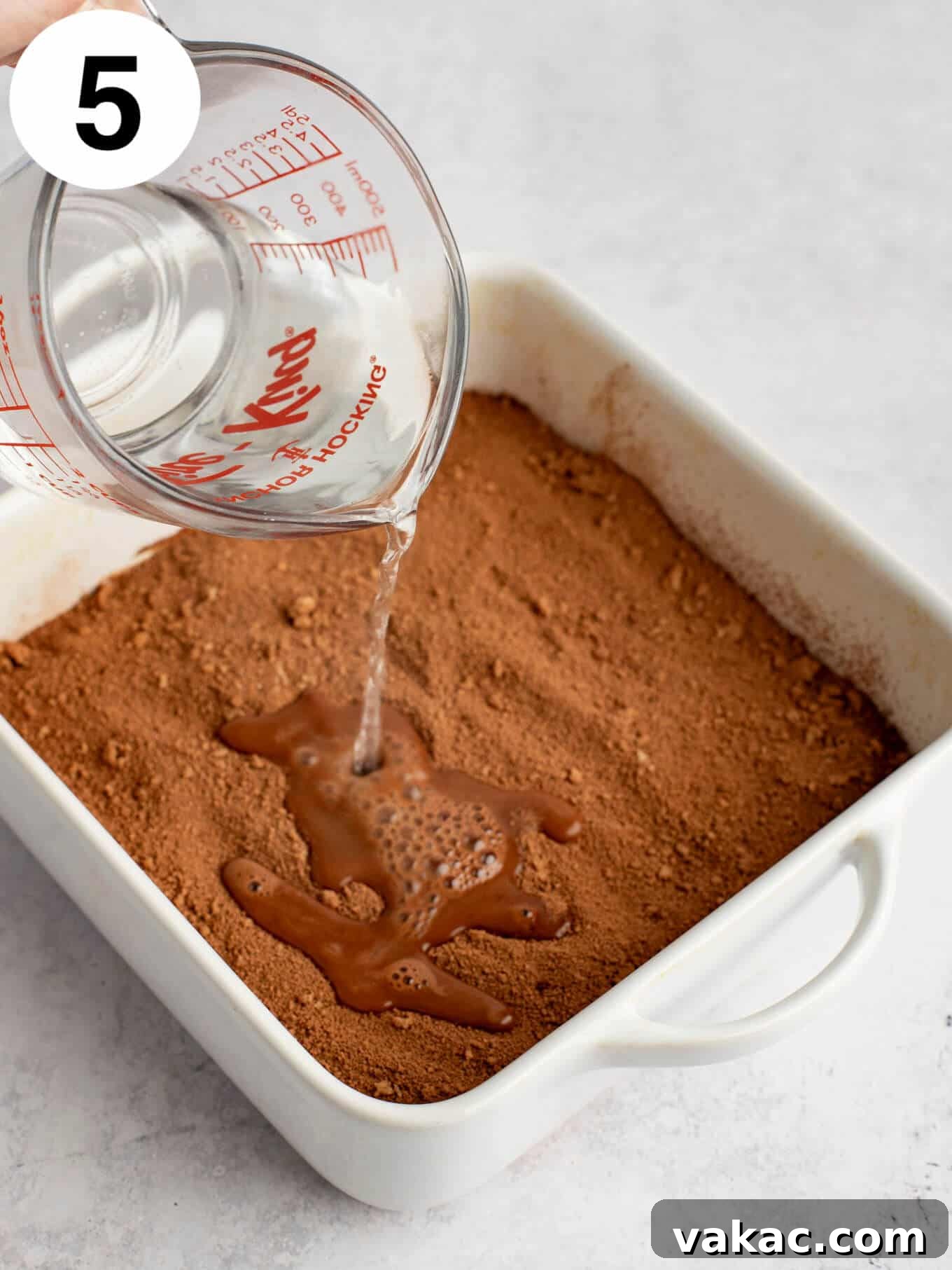 Velvet Chocolate Indulgence 8 A process shot showing water being poured over chocolate cake batter in a baking dish.