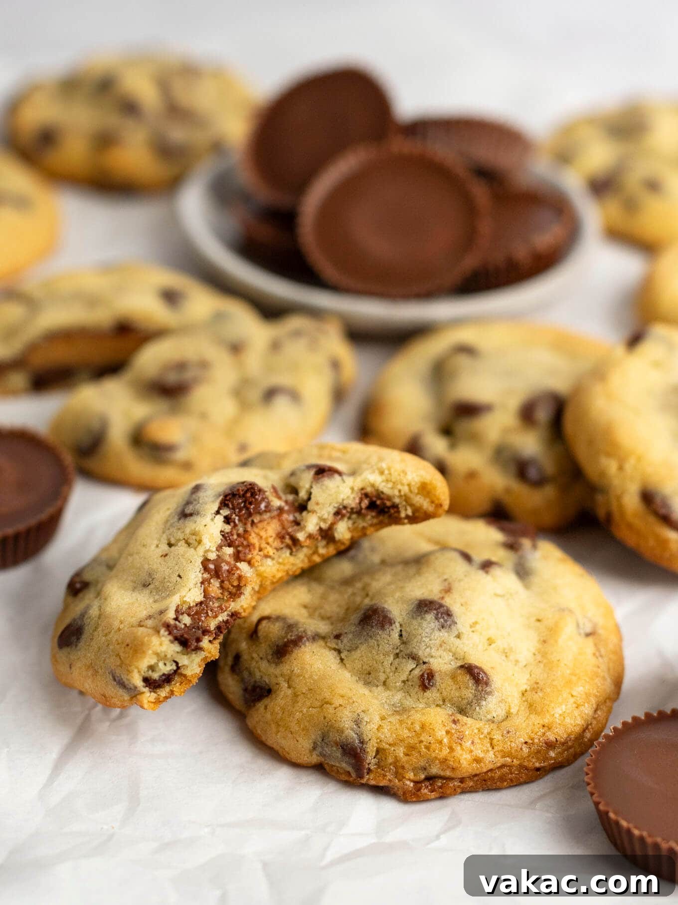 Reese's Peanut Butter Cup Overload Cookies 11 A Reese's stuffed chocolate chip cookie with a bite missing, resting on another cookie, showing the gooey peanut butter center.
