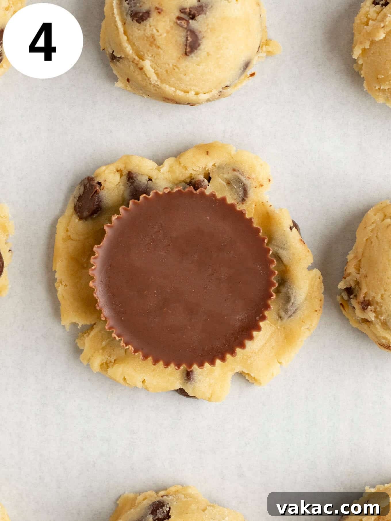 Reese's Peanut Butter Cup Overload Cookies 7 An overhead view of a flattened circle of chocolate chip cookie dough with a Reese's peanut butter cup placed in the middle.