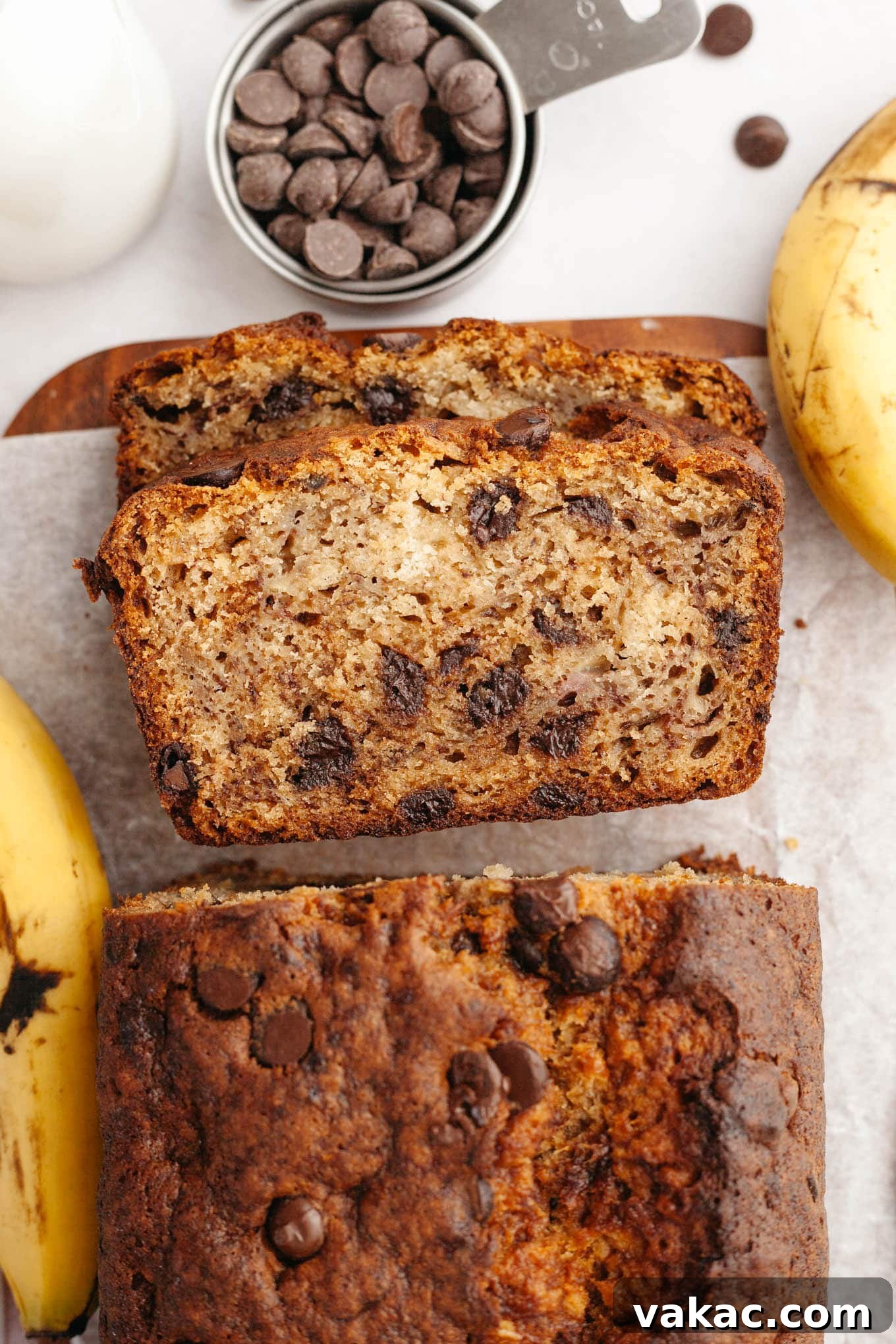 Decadent Chocolate Chip Banana Loaf 2 An overhead view of perfectly sliced chocolate chip banana bread on a wooden board, showcasing its moist texture and abundant chocolate chips.