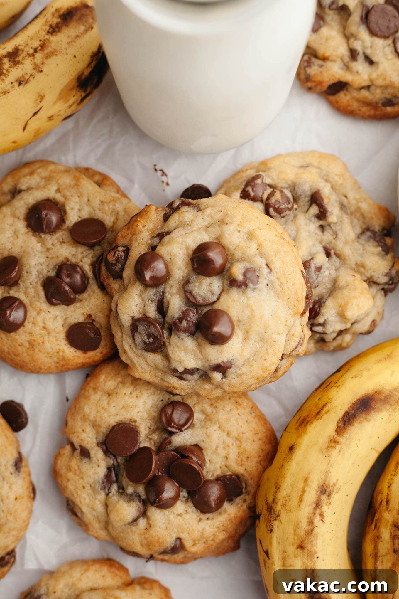 Banana Bliss Chocolate Chip Cookies 7 An overhead view of golden-brown banana chocolate chip cookies next to a bunch of ripe bananas.