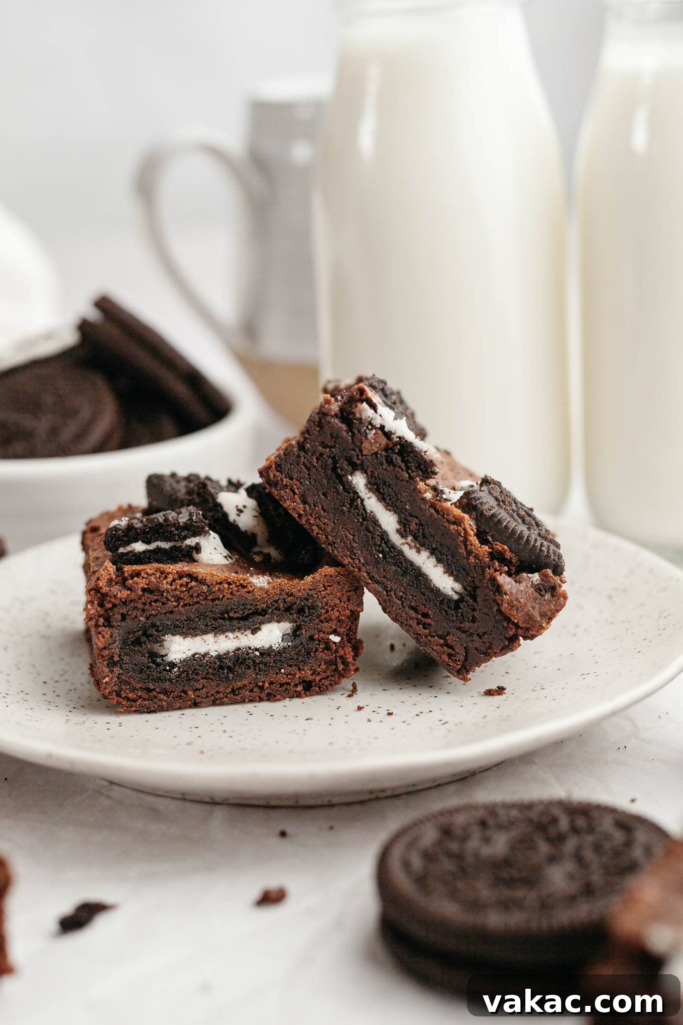 Two rich Oreo stuffed brownies, perfectly cut and presented on a pristine white dessert plate, highlighting their fudgy texture and delicious layers.