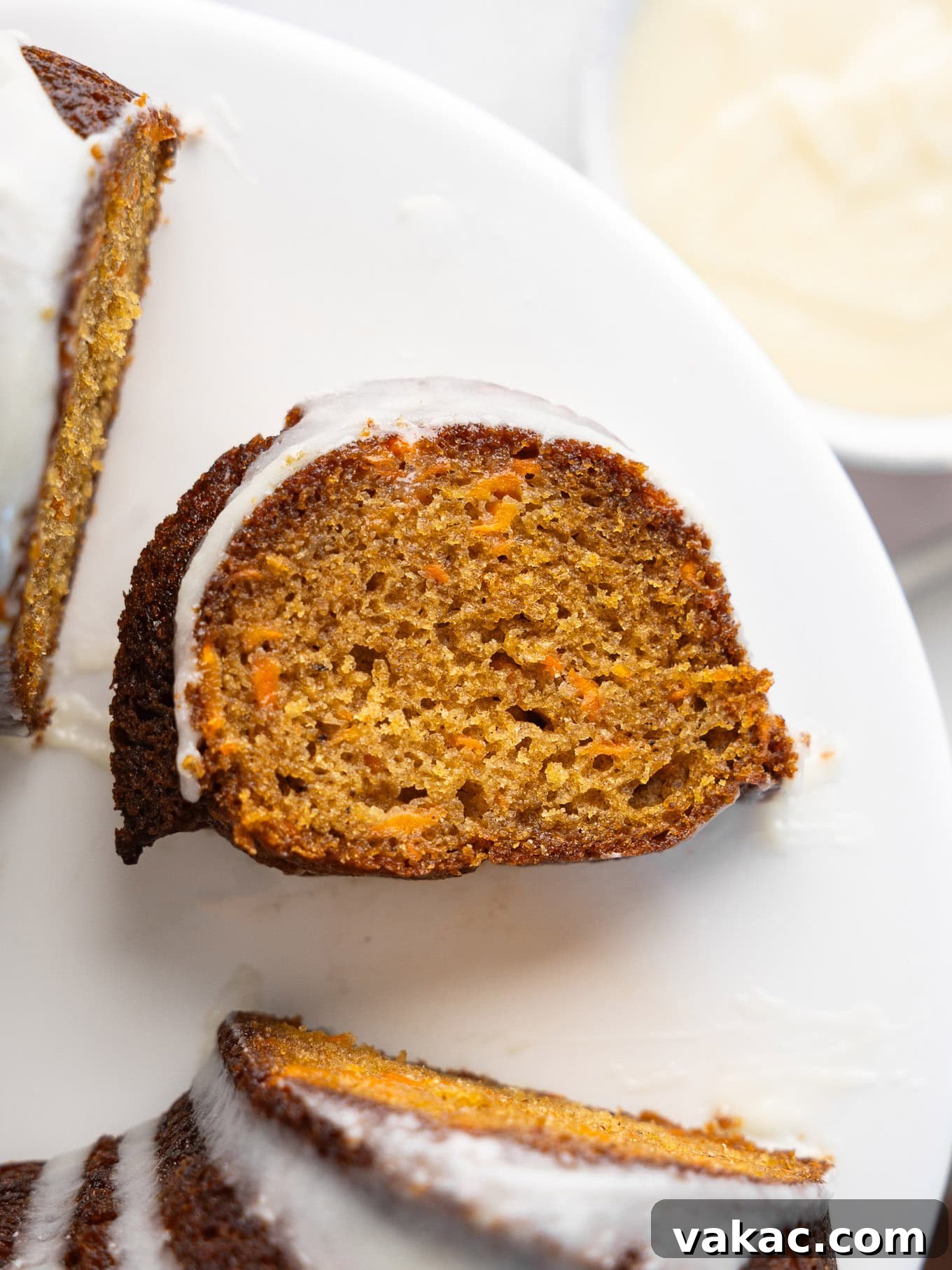 An overhead view of a slice of carrot cake on its side, in the middle of a bundt ring, garnished with cream cheese icing.