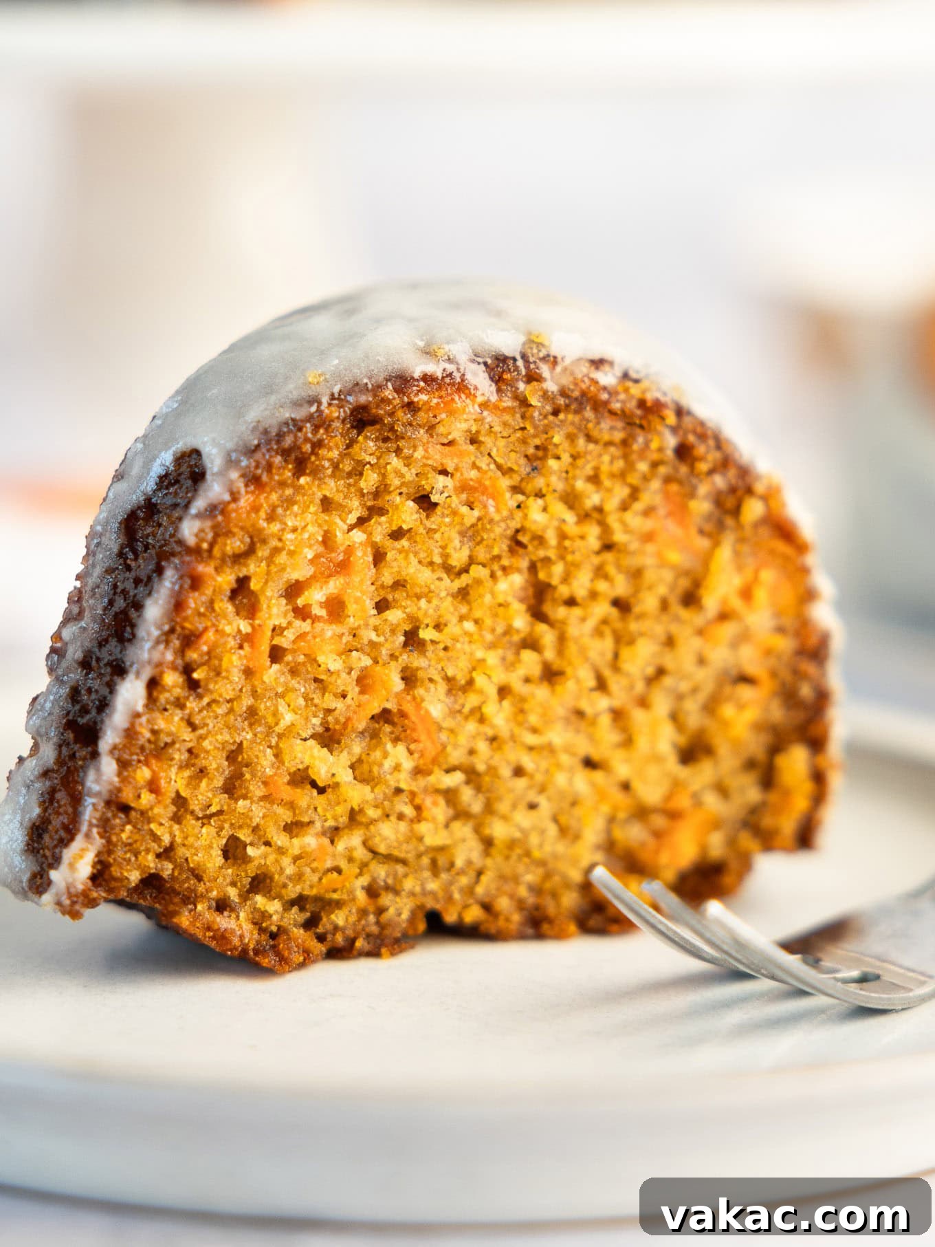 A perfect slice of carrot bundt cake, showing off its moist crumb and rich texture from the side.