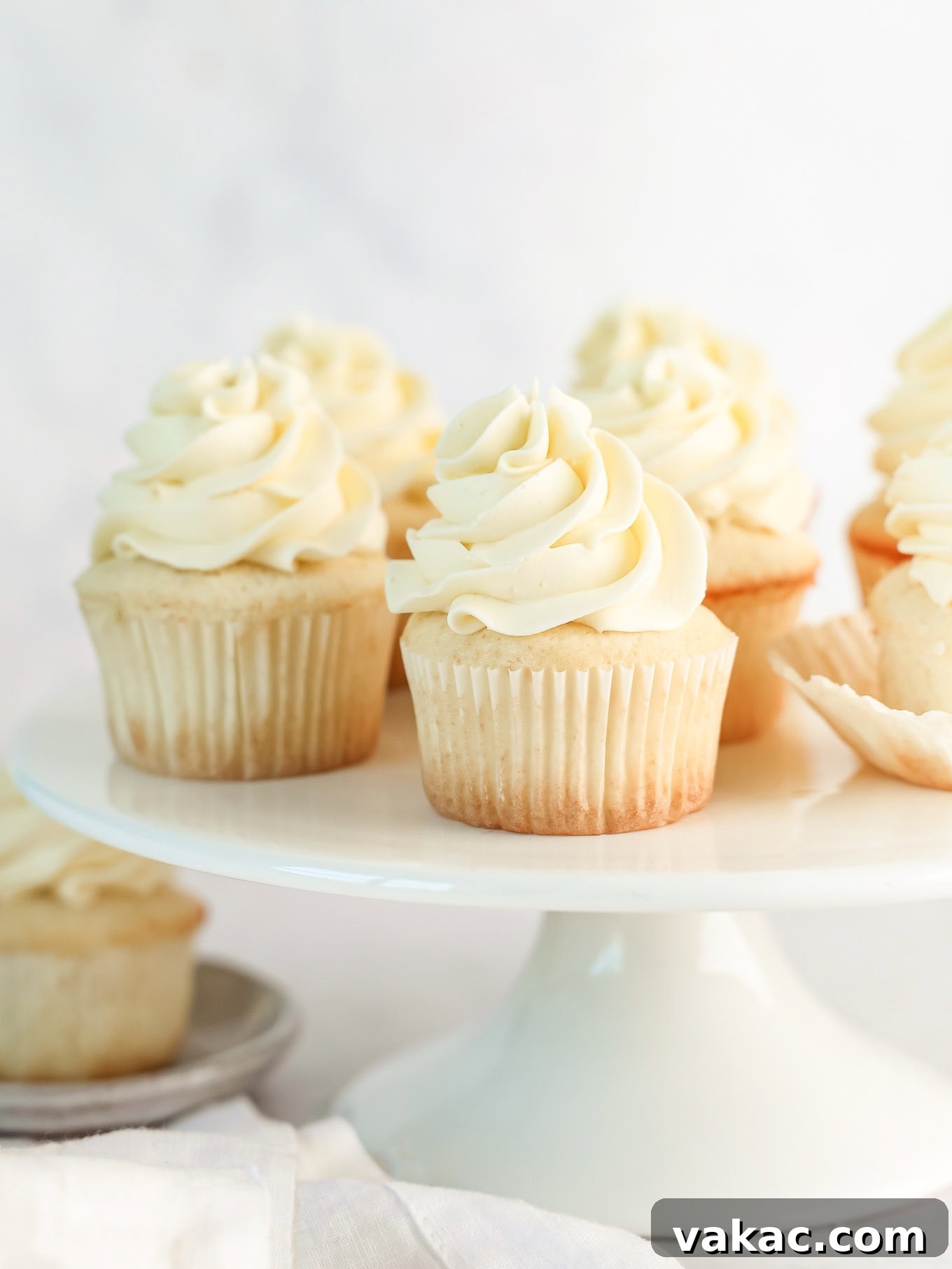 Fluffy White Cupcakes 2 Frosted white cupcakes on a cake stand, elegantly arranged and ready to be served.
