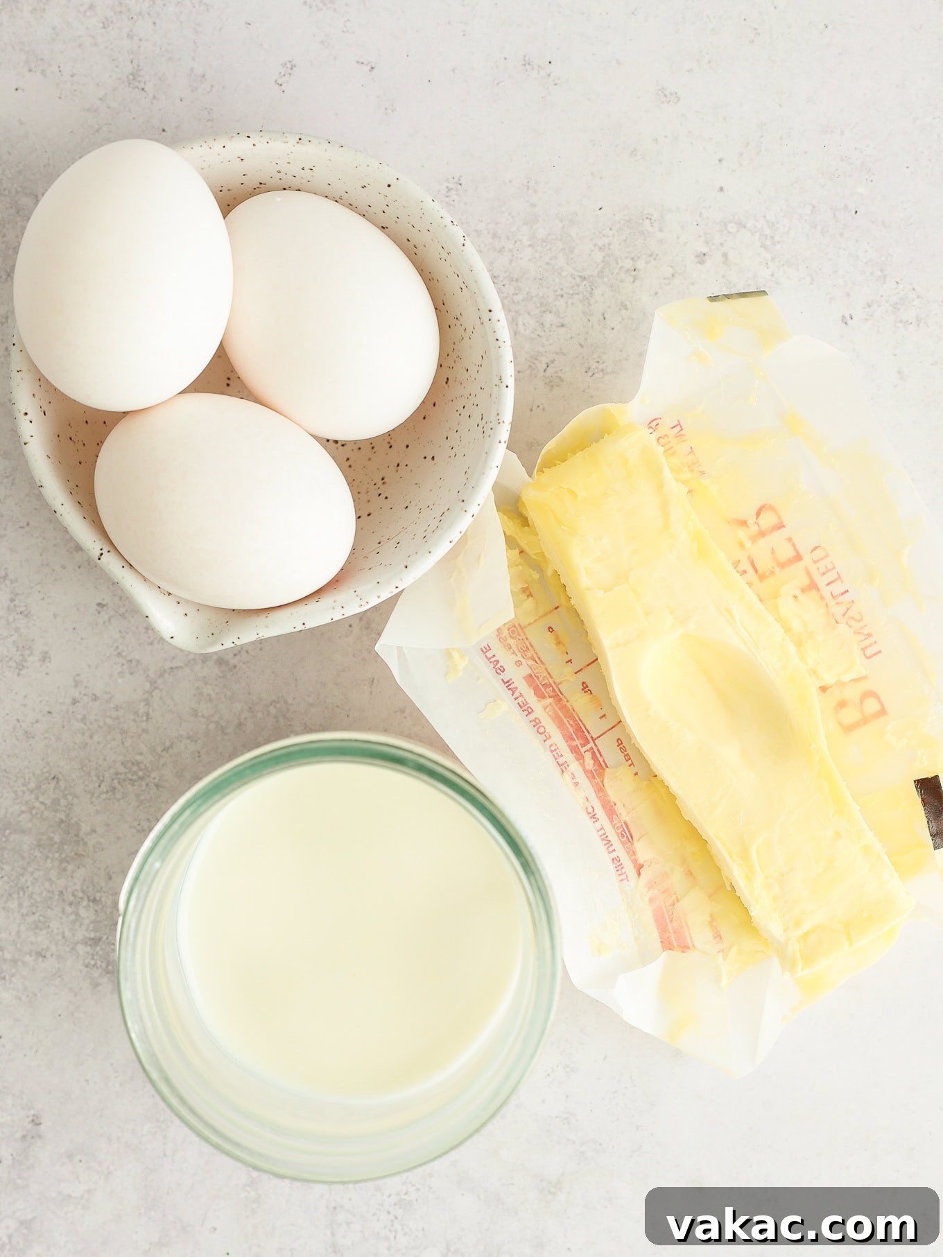 Fluffy White Cupcakes 3 Overhead view of fresh eggs, softened butter, and a bottle of buttermilk, essential for baking.