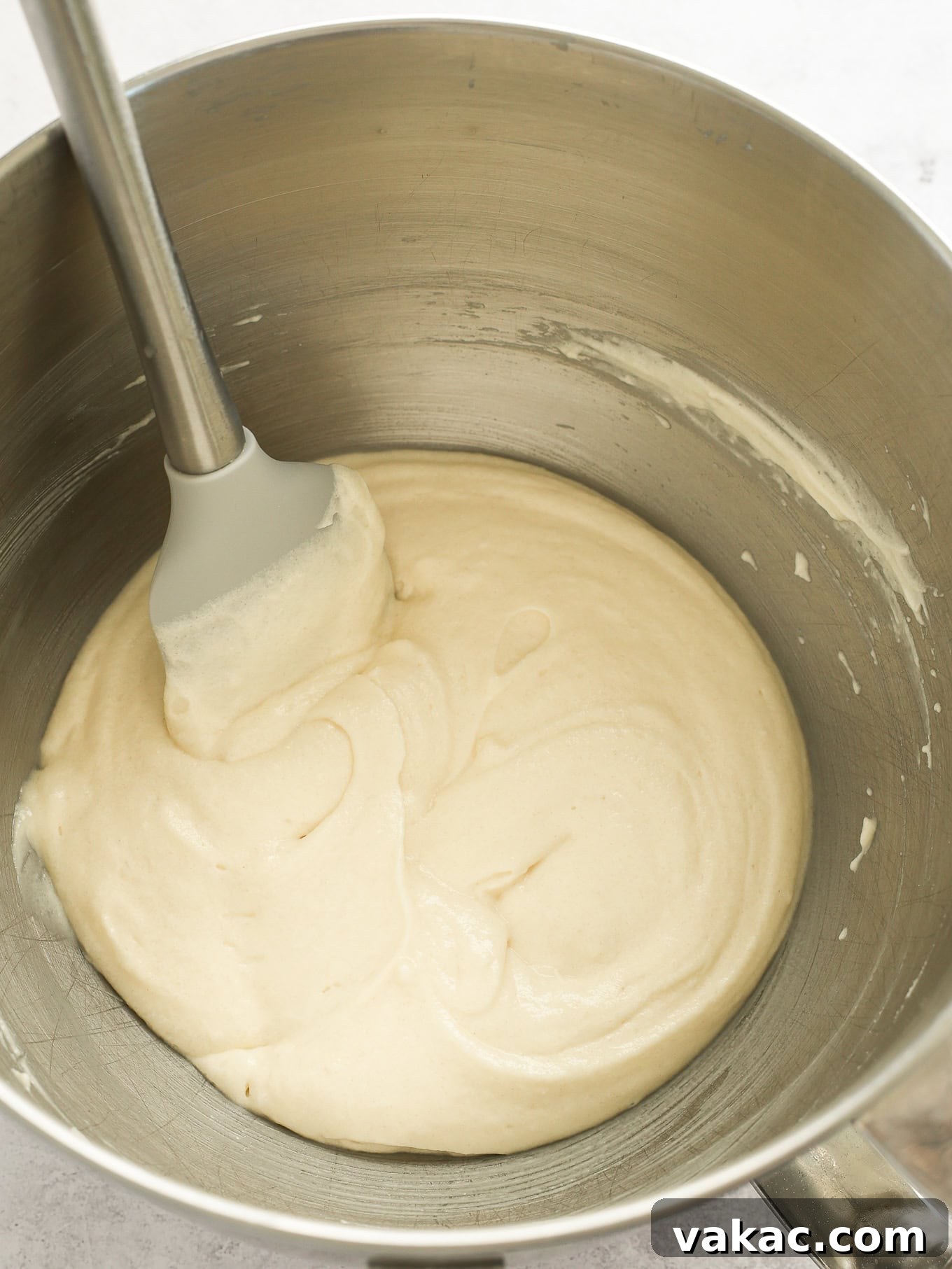 Fluffy White Cupcakes 7 White cupcake batter in a mixing bowl, lightly folded with egg whites, featuring a rubber spatula for gentle incorporation.