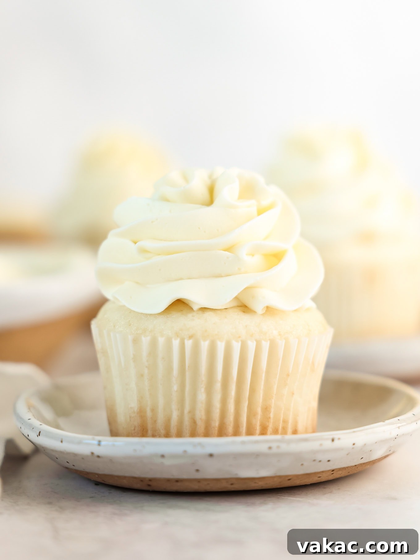 Fluffy White Cupcakes 9 A perfectly baked white cupcake topped with a swirl of vanilla frosting, presented on a simple white plate.