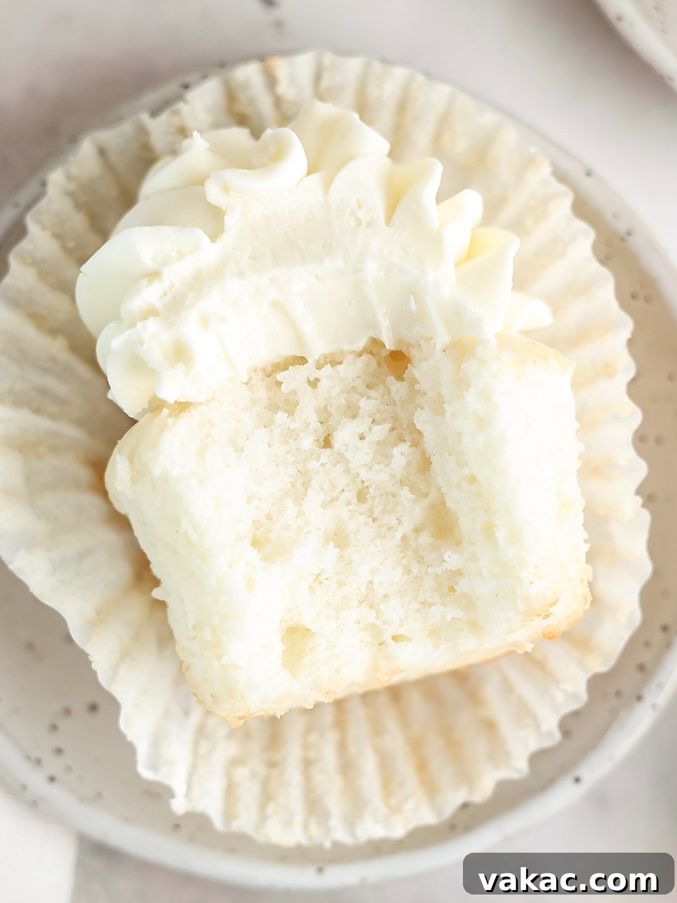 Fluffy White Cupcakes 10 A close-up of a white cupcake lying on its side, revealing its soft, fluffy interior with a bite taken out.