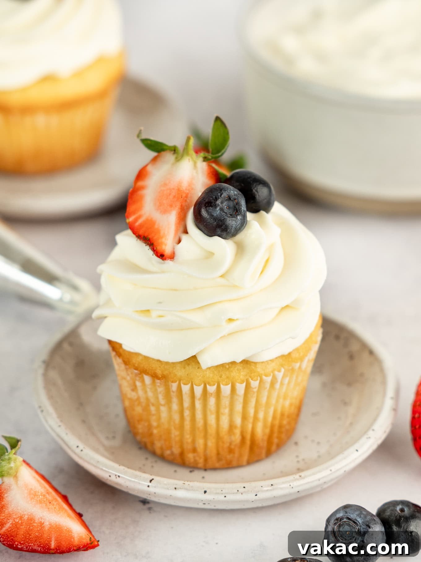 Fluffy Cream Cheese Cloud 2 A cupcake elegantly topped with light and fluffy whipped cream cheese frosting, adorned with fresh, vibrant berries, showcasing the perfect texture and presentation for a delightful dessert.