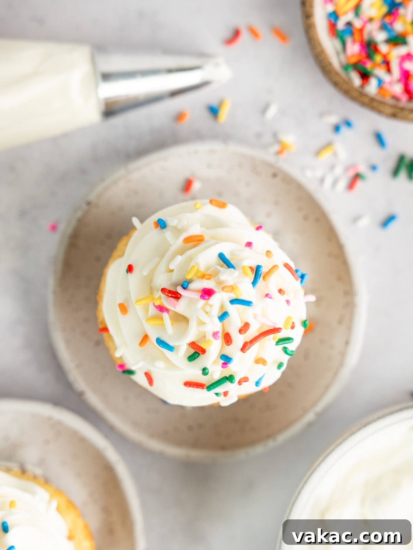 Fluffy Cream Cheese Cloud 8 An overhead view of a perfectly frosted cupcake with light whipped cream cheese frosting, adorned with colorful sprinkles, showcasing its delightful appearance and readiness to be enjoyed.