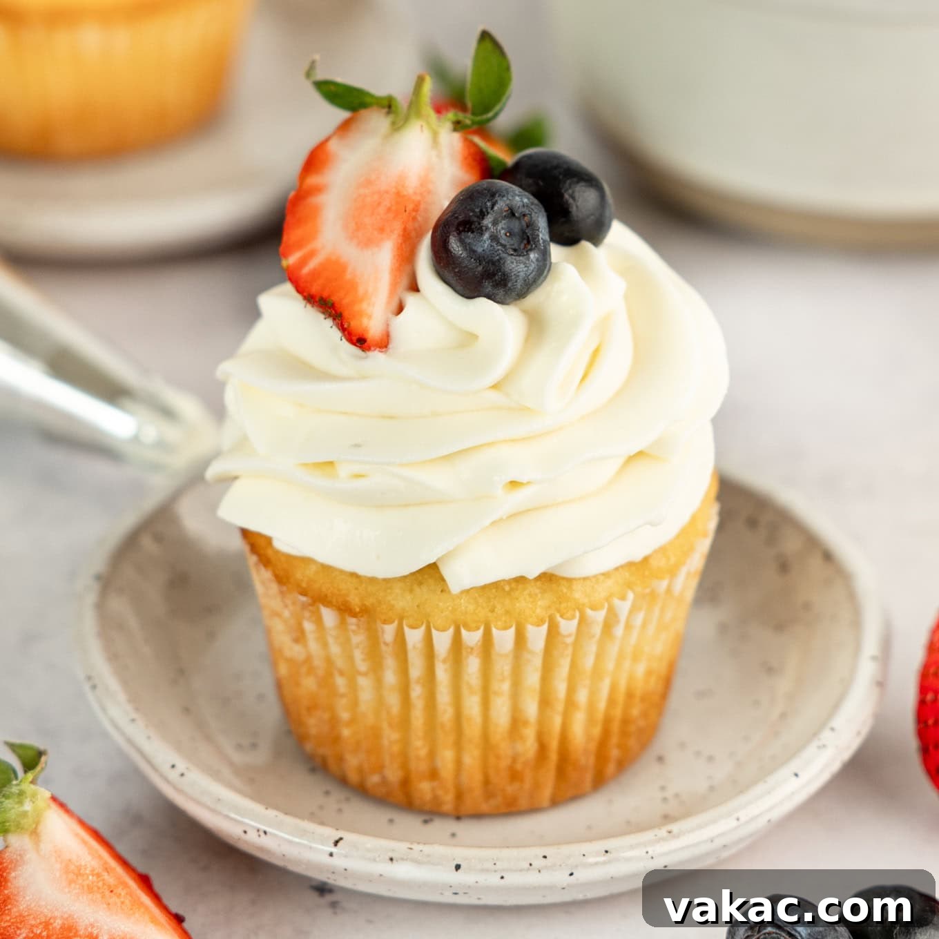 Fluffy Cream Cheese Cloud 9 A cupcake topped with whipped cream cheese frosting and fresh berries.