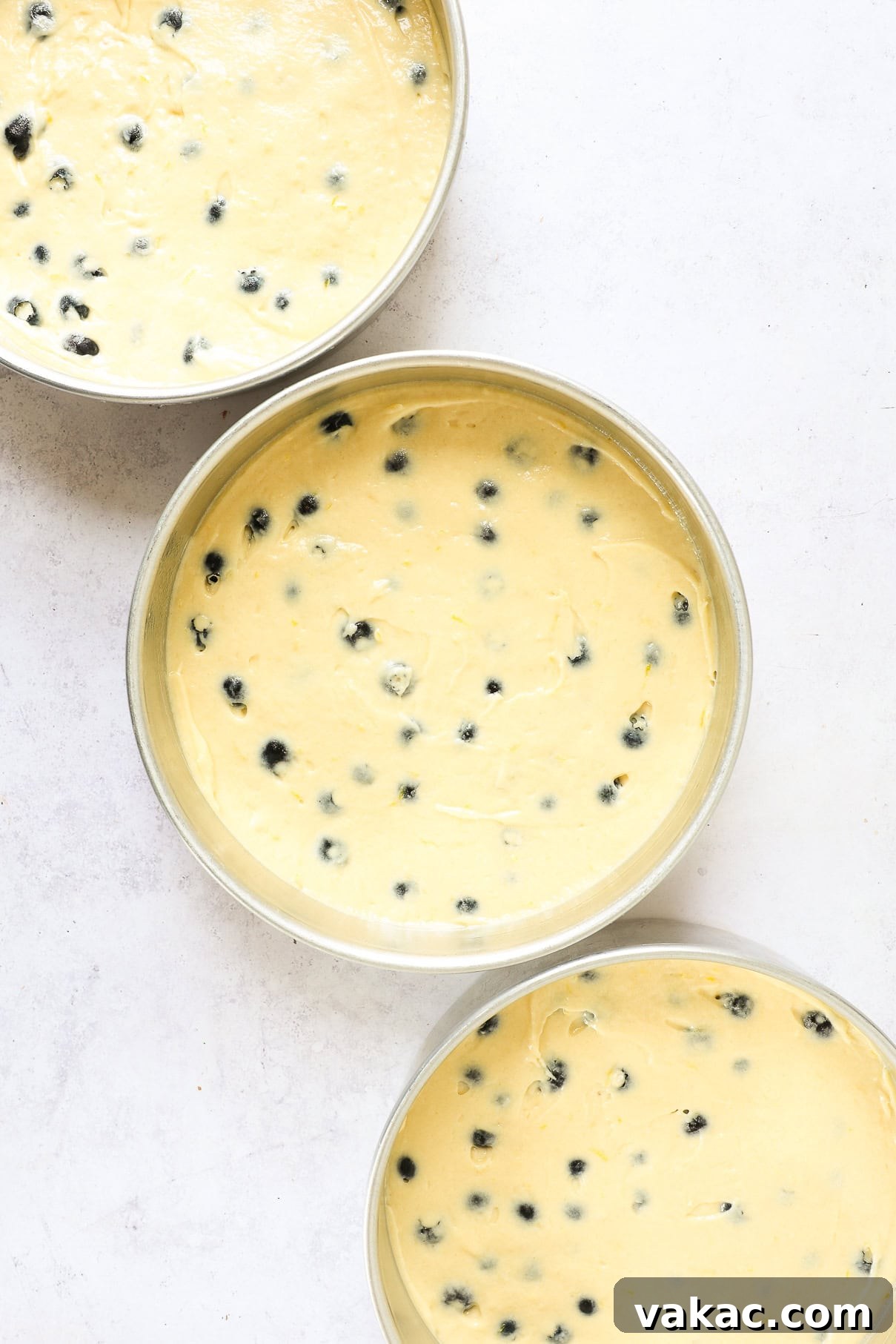 Sunshine Berry Cloud Cake 8 Three round cake pans filled evenly with lemon blueberry cake batter, showing even distribution of berries.