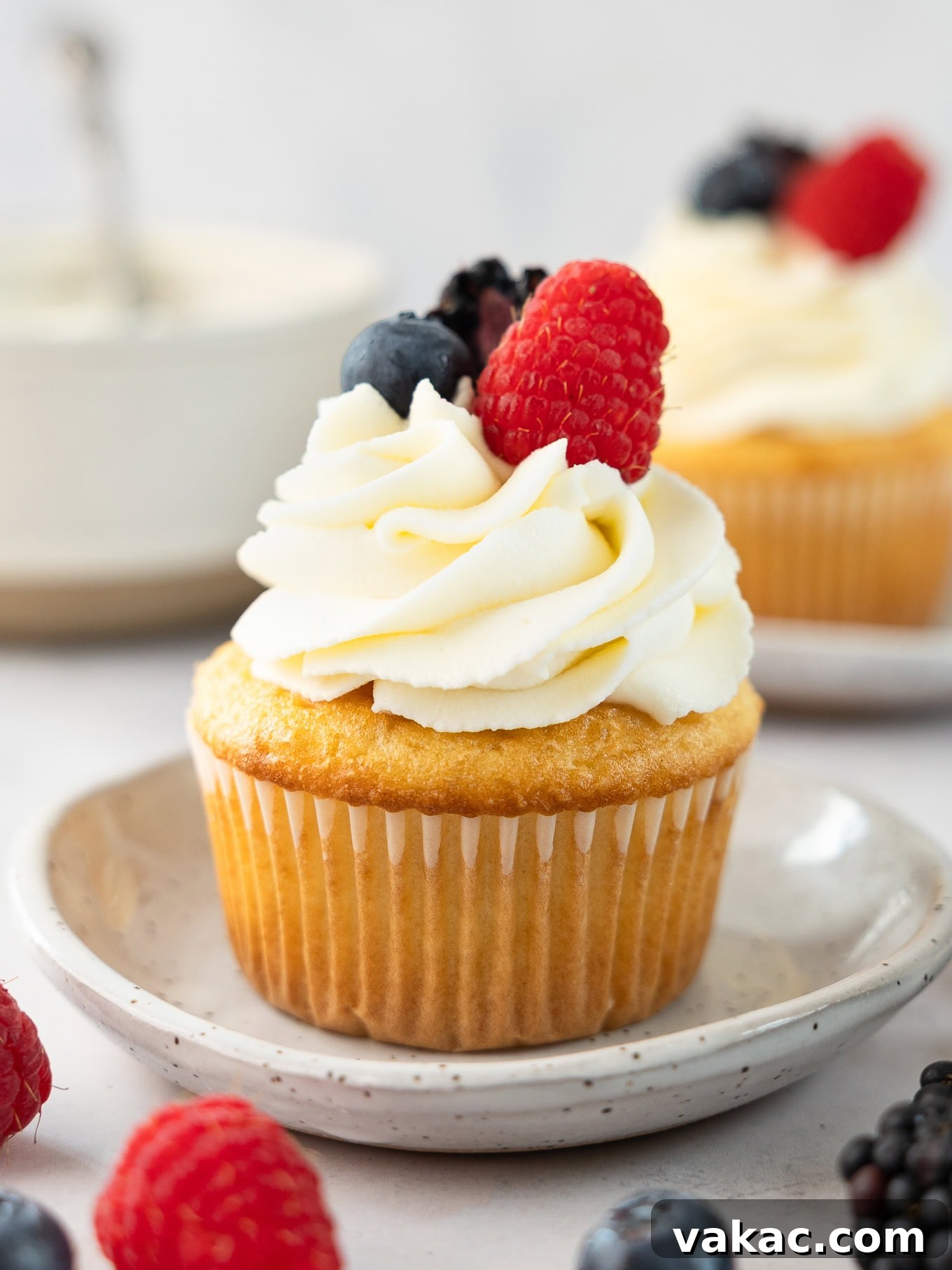 A vanilla cupcake topped with mascarpone frosting and fresh berries, showcasing its light and airy texture.