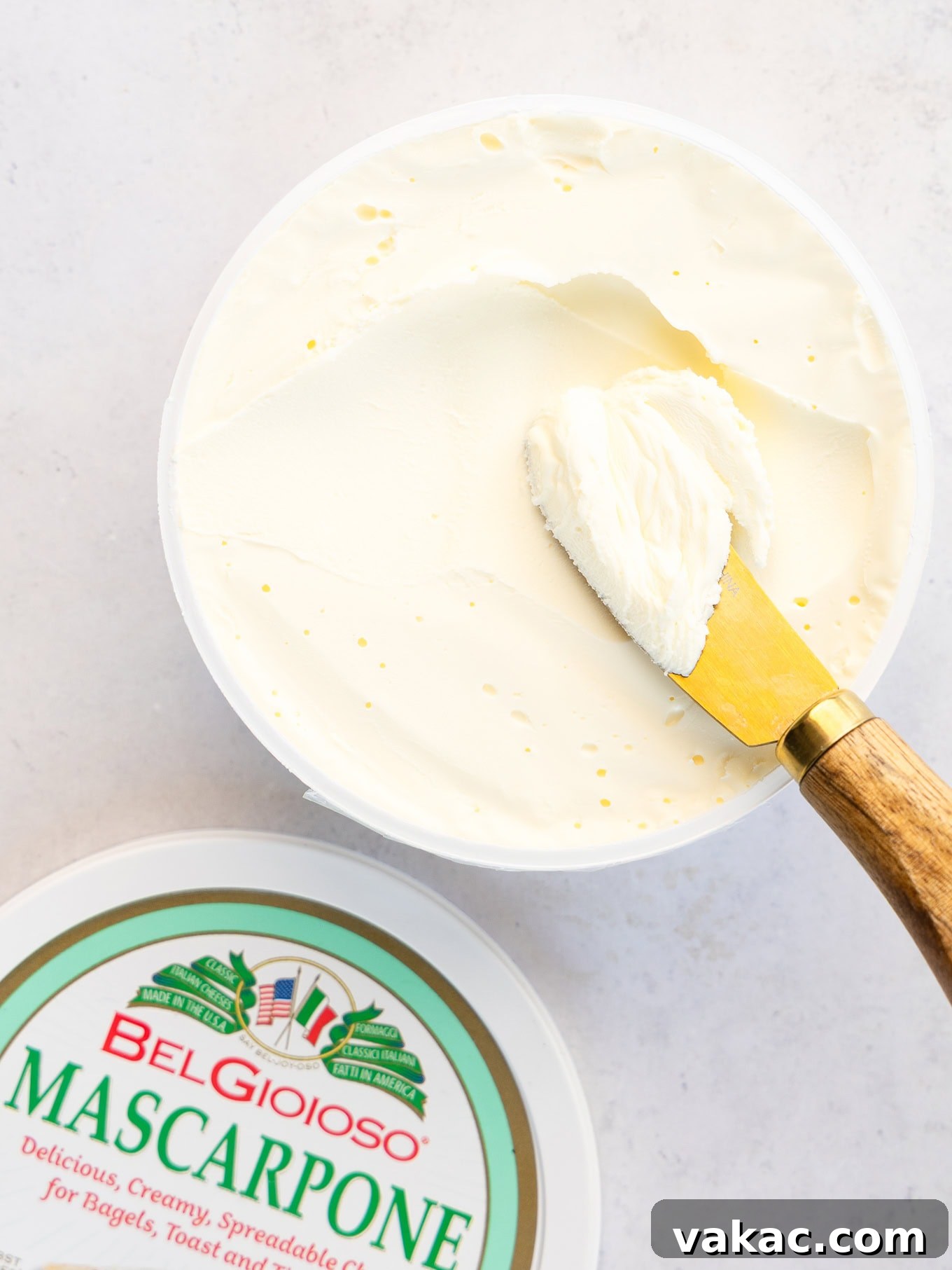 A container of mascarpone cheese with a knife in it, illustrating the primary ingredient.