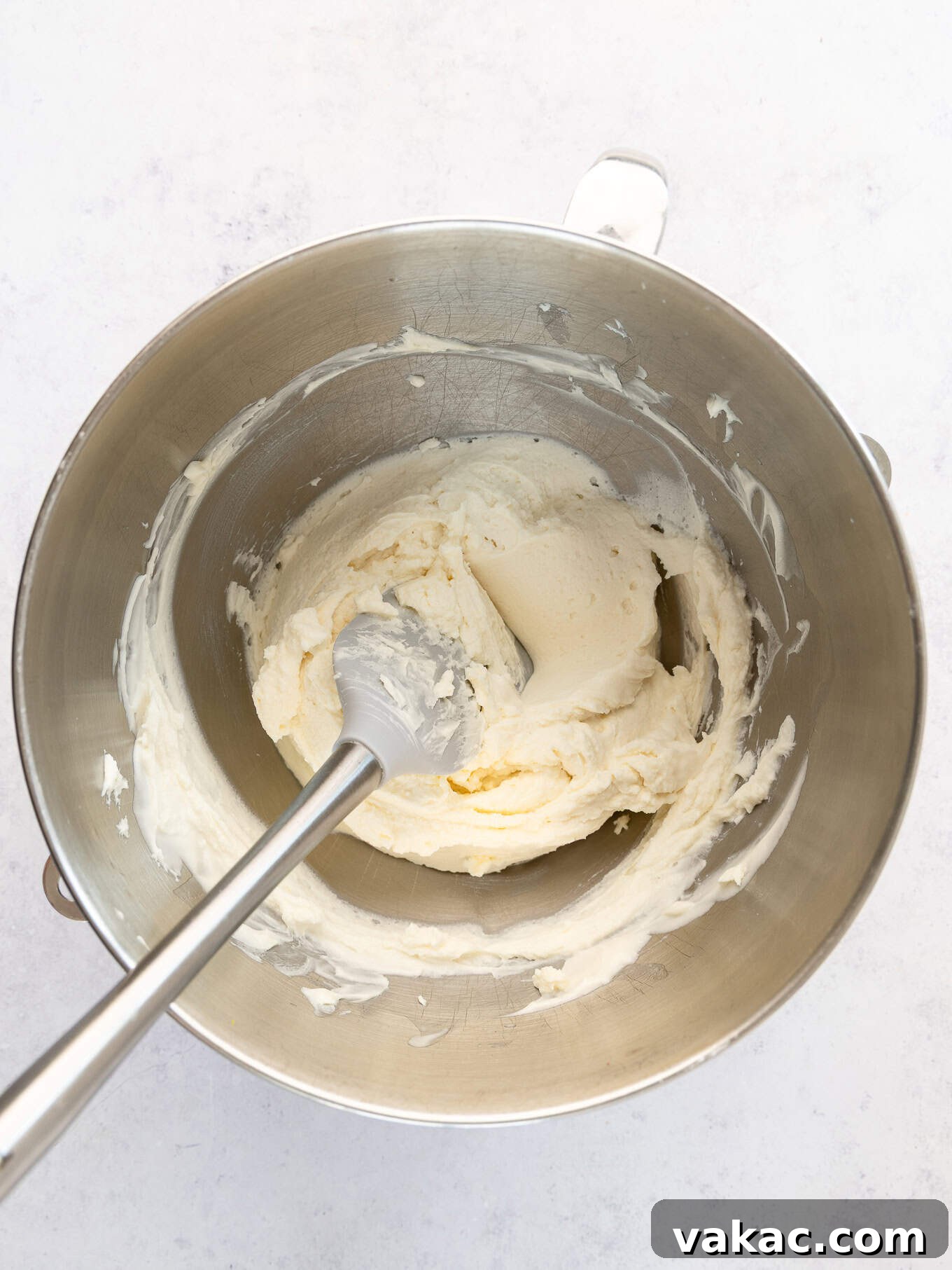 An overhead view of mascarpone frosting in the bowl of a stand mixer, demonstrating the smooth final consistency.
