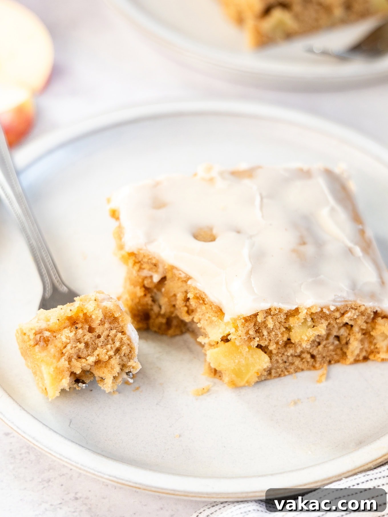 Spiced Apple Fritter Bake 2 A slice of apple fritter cake, with a piece speared on a fork, showcasing its moist texture and rich apple filling.
