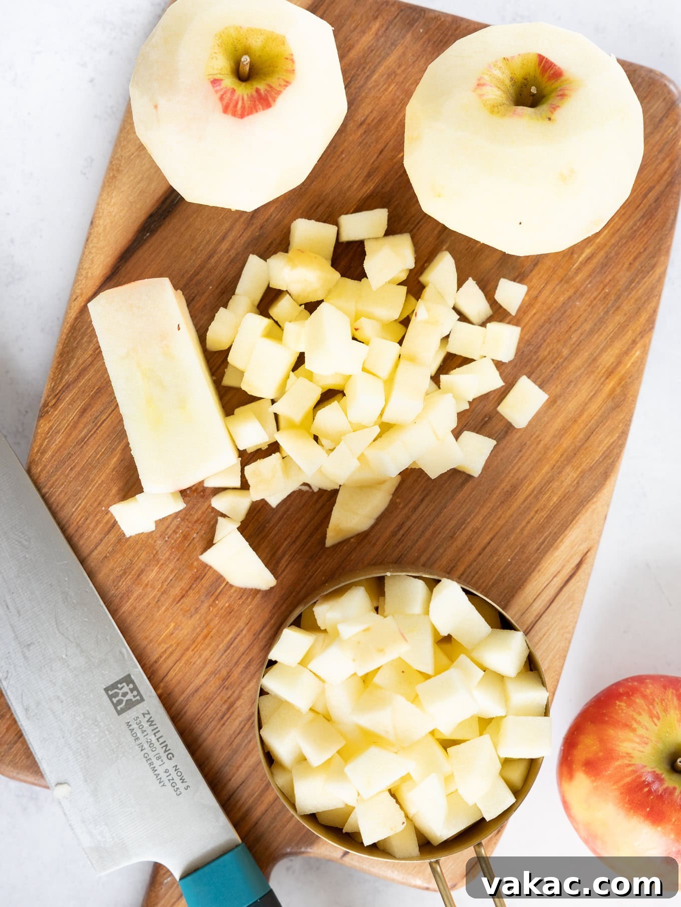 Spiced Apple Fritter Bake 4 Peeled and chopped apples on a cutting board, perfectly prepared for the cake batter.