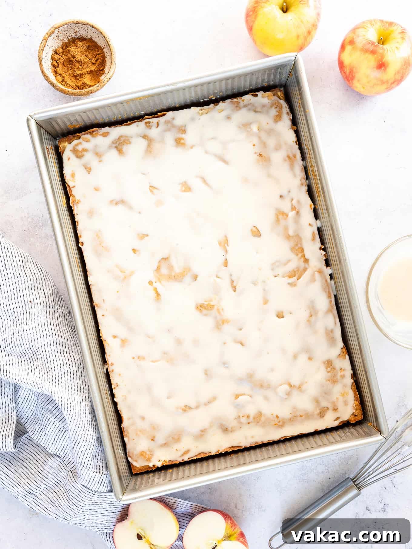 Spiced Apple Fritter Bake 6 An apple fritter cake in a pan, beautifully baked and iced with vanilla glaze.