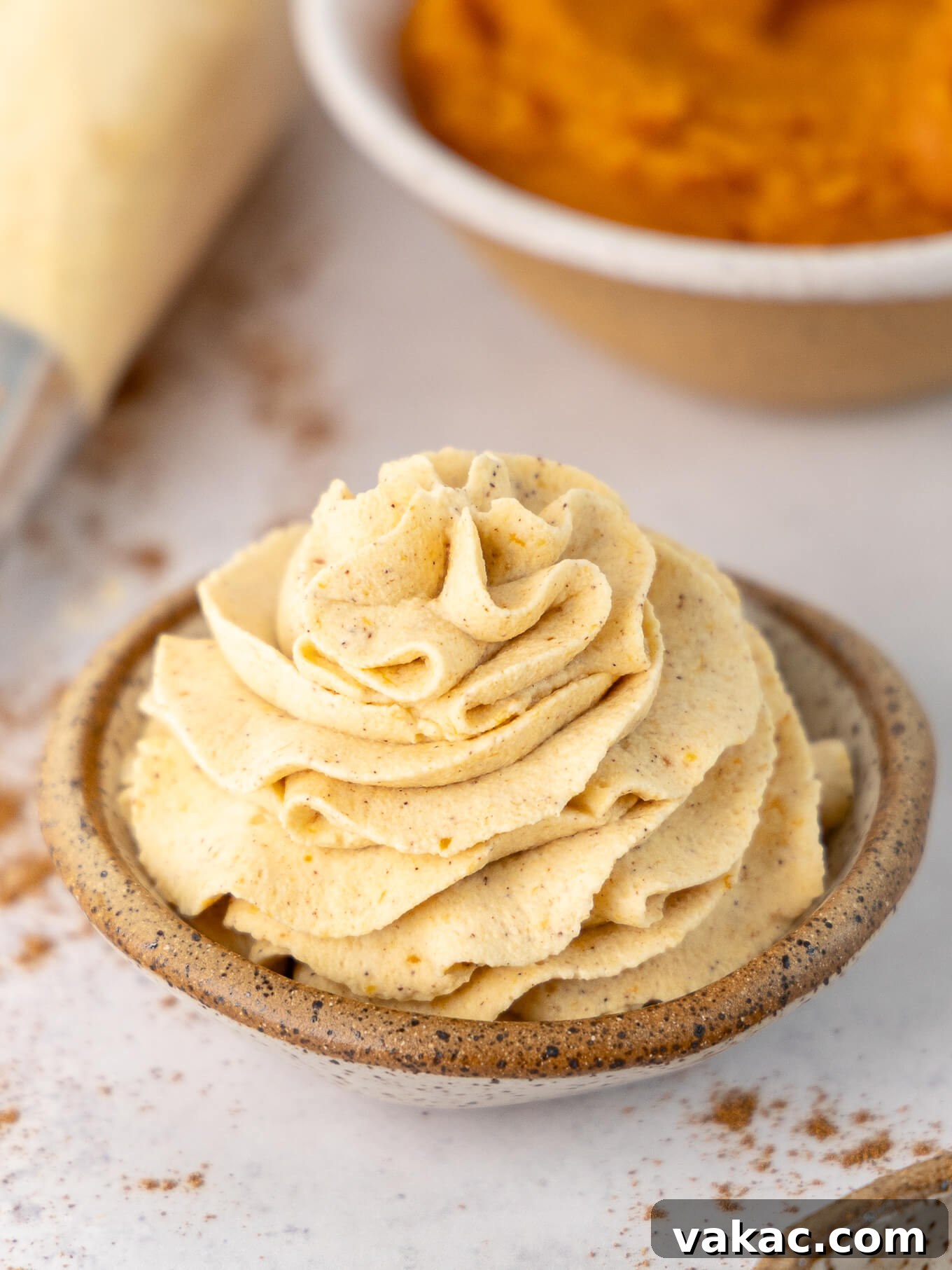 A small bowl elegantly piped with homemade pumpkin spice whipped cream, ready to adorn any autumn dessert.