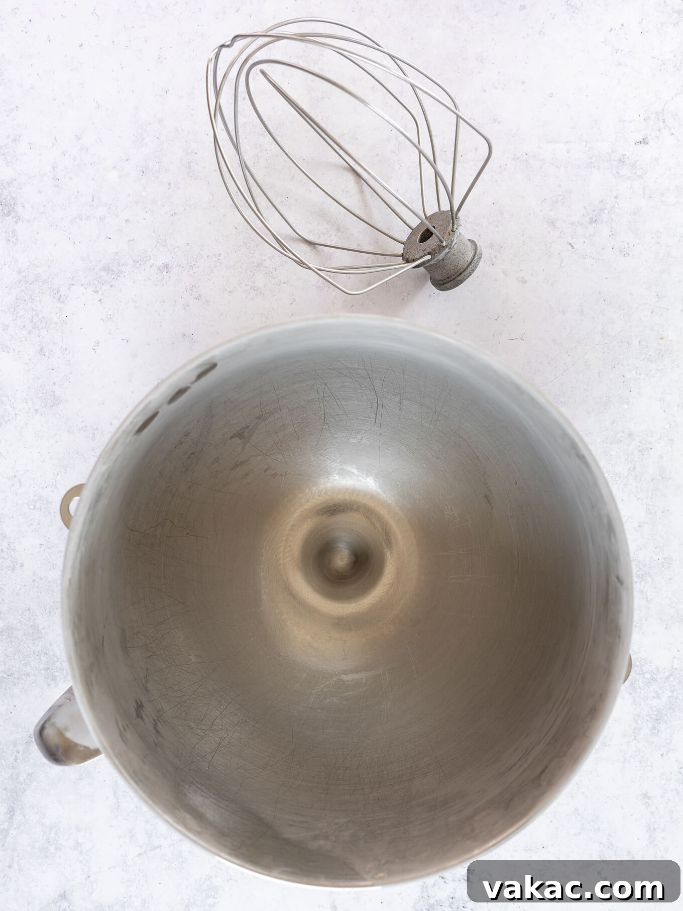 A shiny, clean metal mixing bowl with a whisk attachment stands ready, signifying the start of the whipping process.